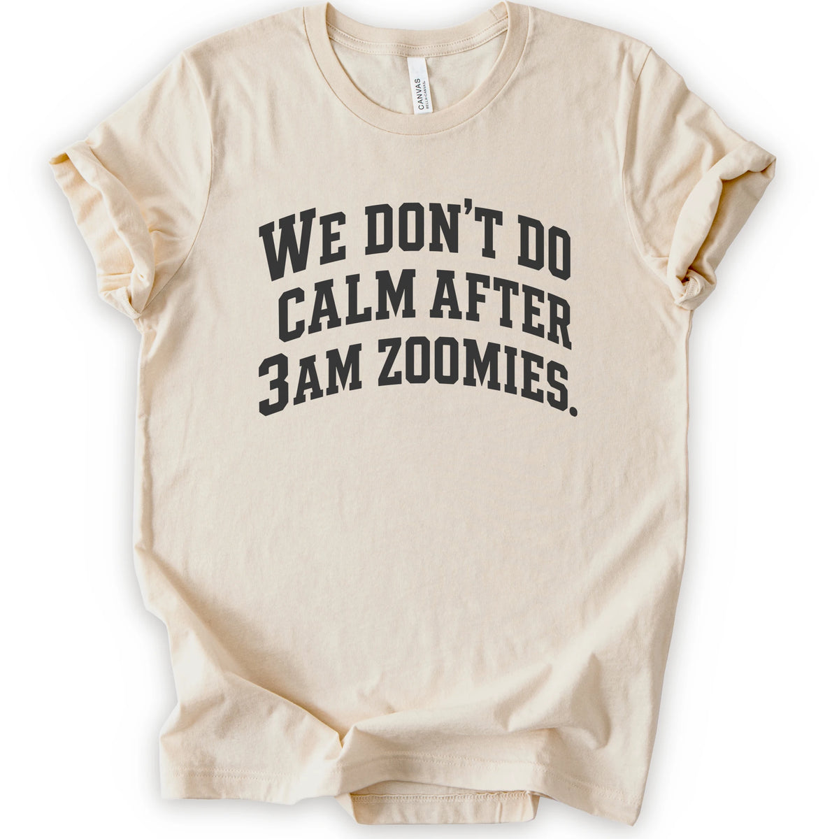 A natural short-sleeve crewneck t-shirt with the text 'WE DON'T DO CALM AFTER 3AM ZOOMIES.' printed in a distressed black font on the front.