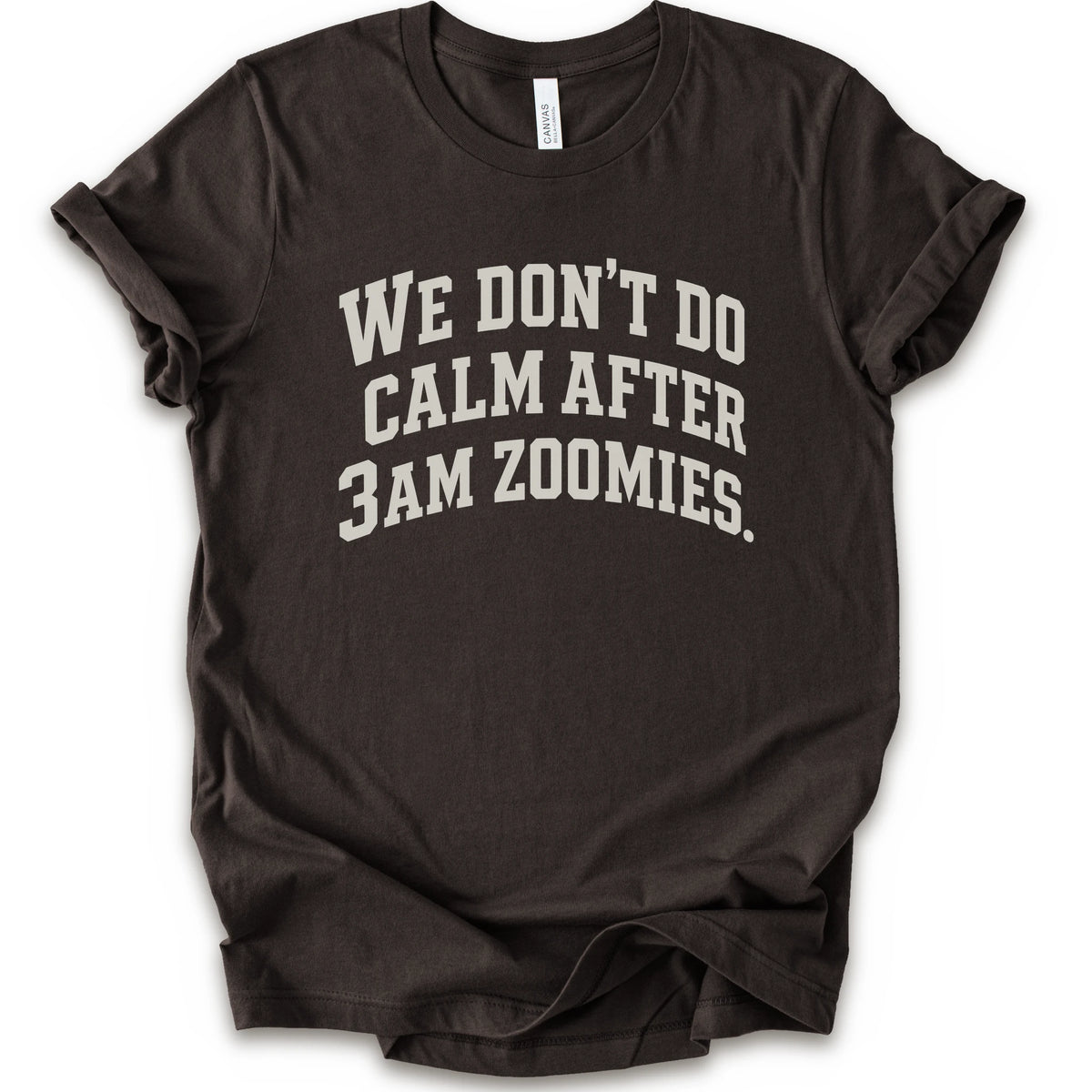 A brown short-sleeve crewneck t-shirt with the text 'WE DON'T DO CALM AFTER 3AM ZOOMIES.' printed in a distressed white font on the front.
