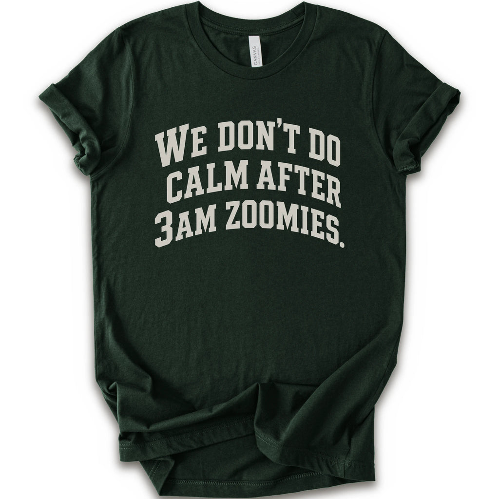 A forest short-sleeve crewneck t-shirt with the text 'WE DON'T DO CALM AFTER 3AM ZOOMIES.' printed in a distressed white font on the front.