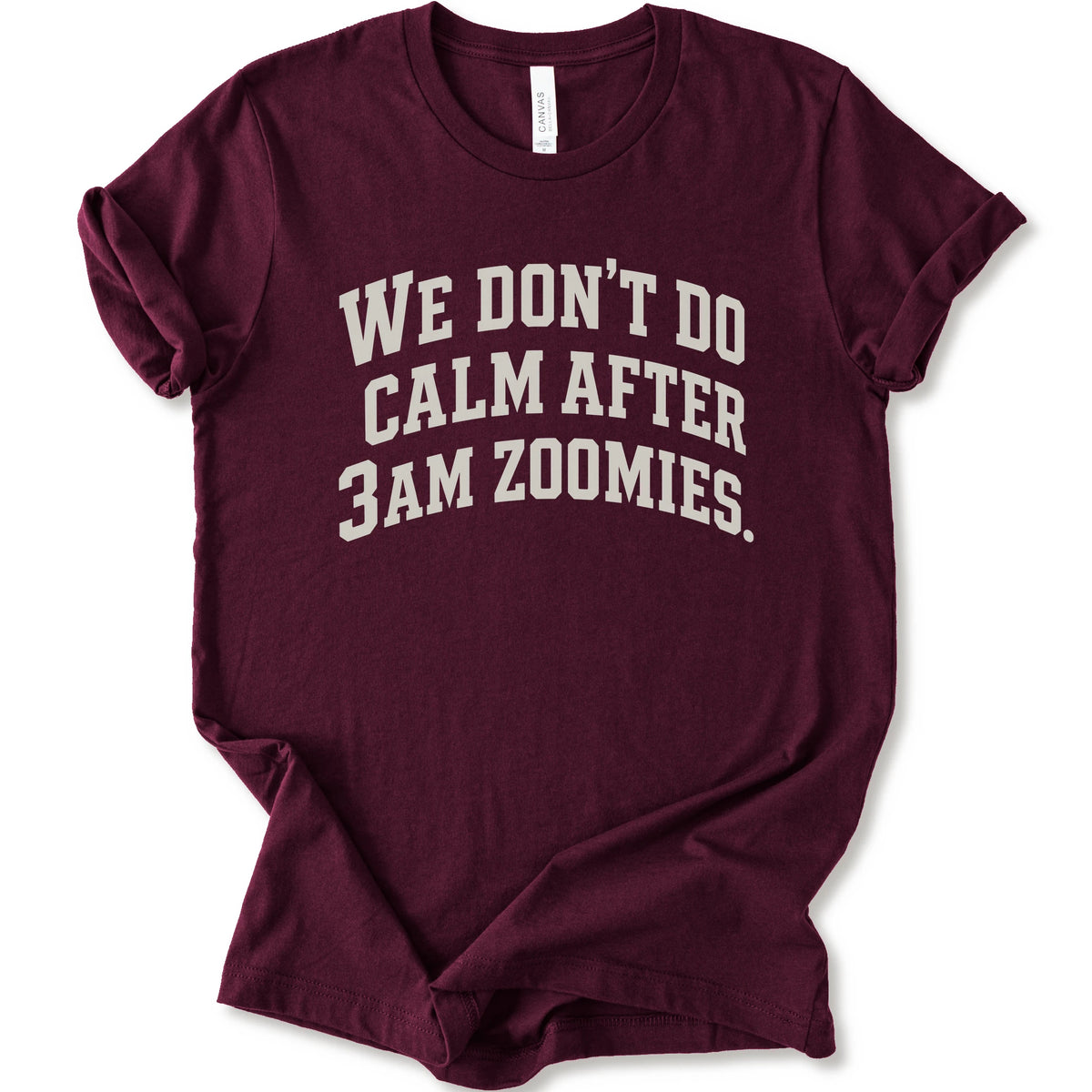 A maroon short-sleeve crewneck t-shirt with the text 'WE DON'T DO CALM AFTER 3AM ZOOMIES.' printed in a distressed white font on the front.
