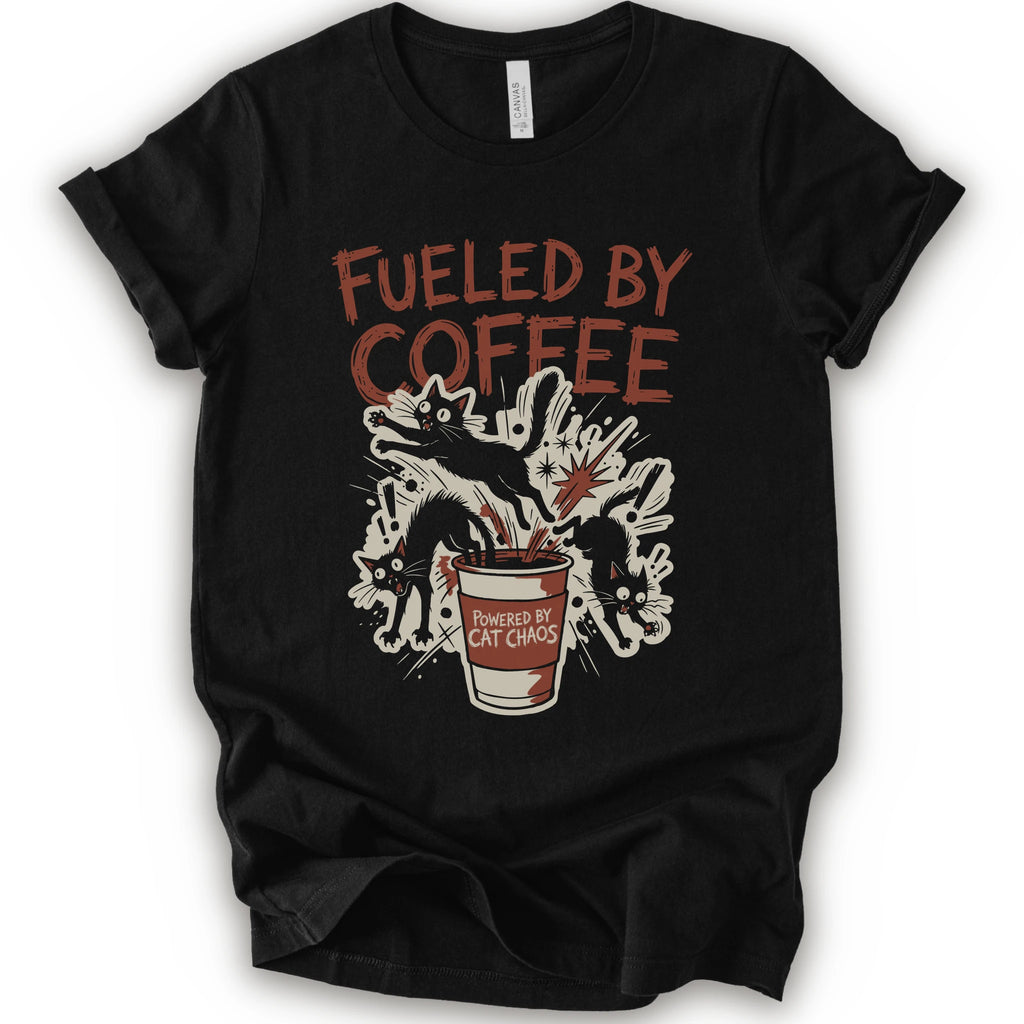 A black short-sleeve graphic t-shirt laid flat on a white background. The shirt features a distressed graphic print with the text 'FUELED BY COFFEE' in a reddish-brown color, above an illustration of black cats emerging from a coffee cup labeled 'POWERED BY CAT CHAOS'.
