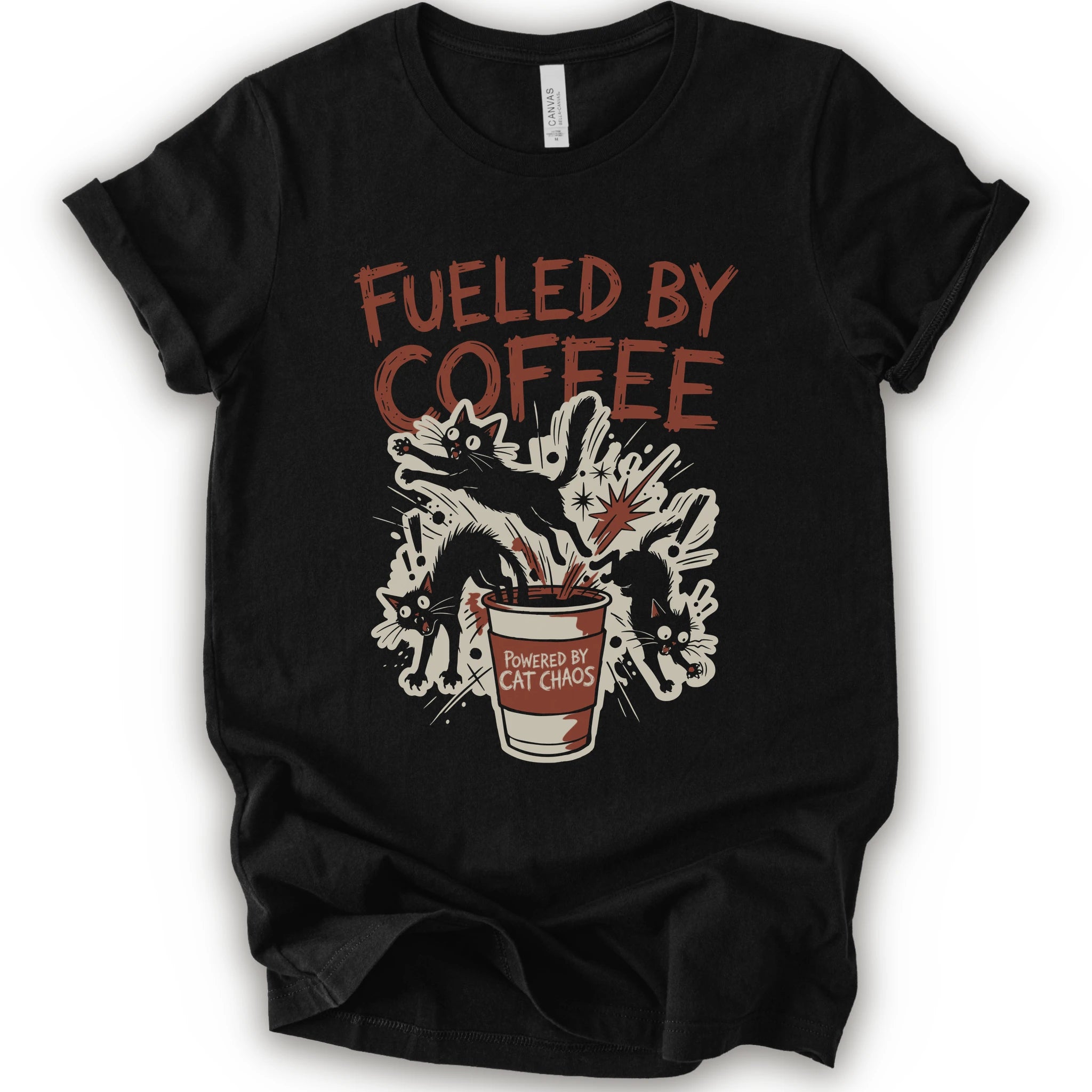A black short-sleeve graphic t-shirt laid flat on a white background. The shirt features a distressed graphic print with the text 'FUELED BY COFFEE' in a reddish-brown color, above an illustration of black cats emerging from a coffee cup labeled 'POWERED BY CAT CHAOS'.