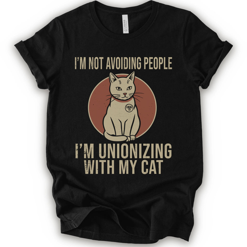 A black short-sleeve crewneck T-shirt with a retro cat graphic and “I’m Not Avoiding People, I’m Unionizing With My Cat” text.