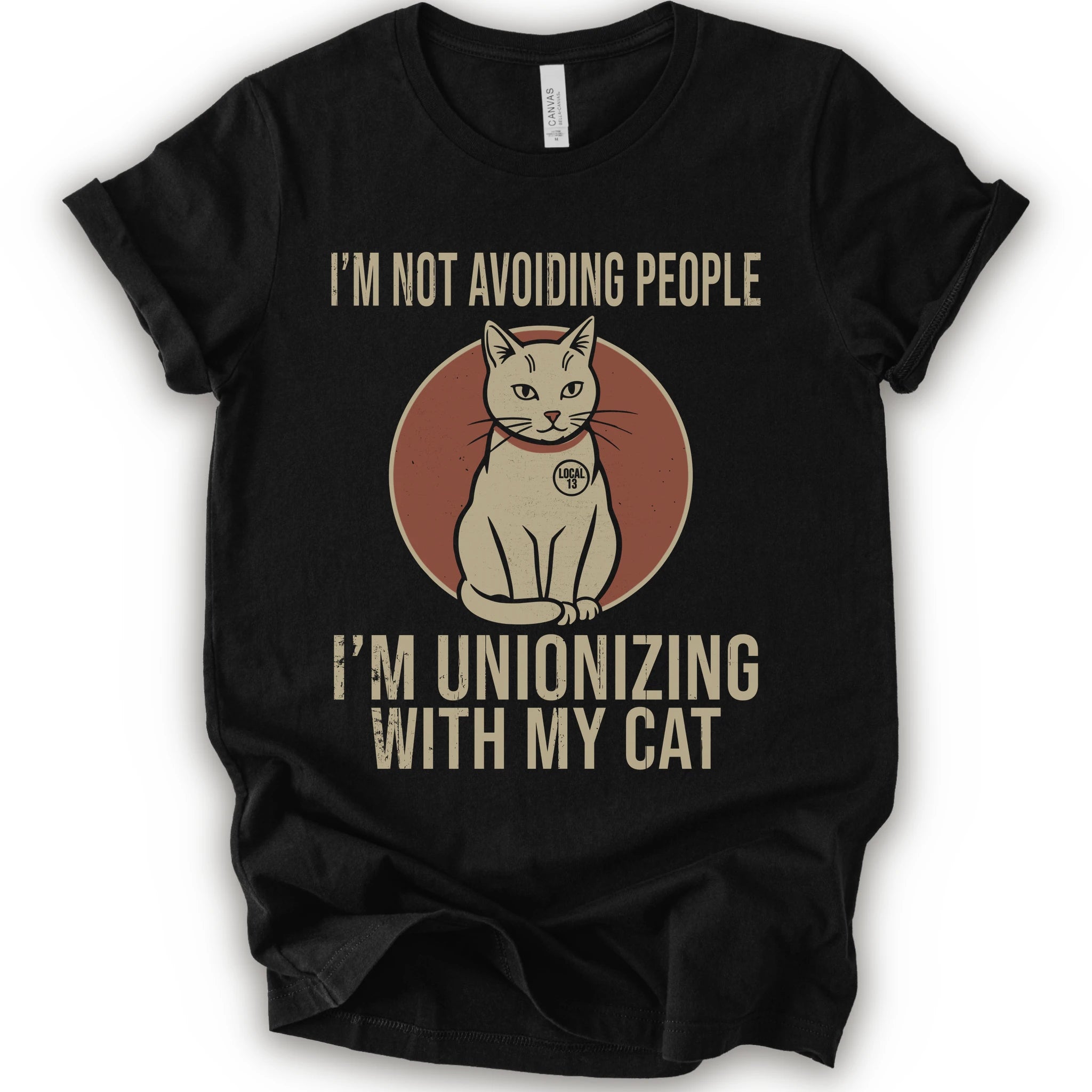 A black short-sleeve crewneck T-shirt with a retro cat graphic and “I’m Not Avoiding People, I’m Unionizing With My Cat” text.