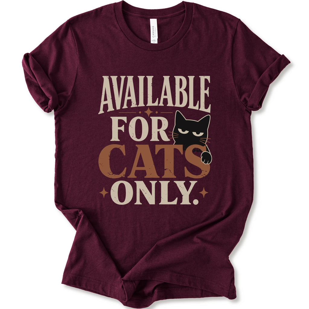 A maroon short-sleeve t-shirt with a distressed graphic that reads 'AVAILABLE FOR CATS ONLY.' in beige and brown-orange lettering, featuring a black cat illustration.