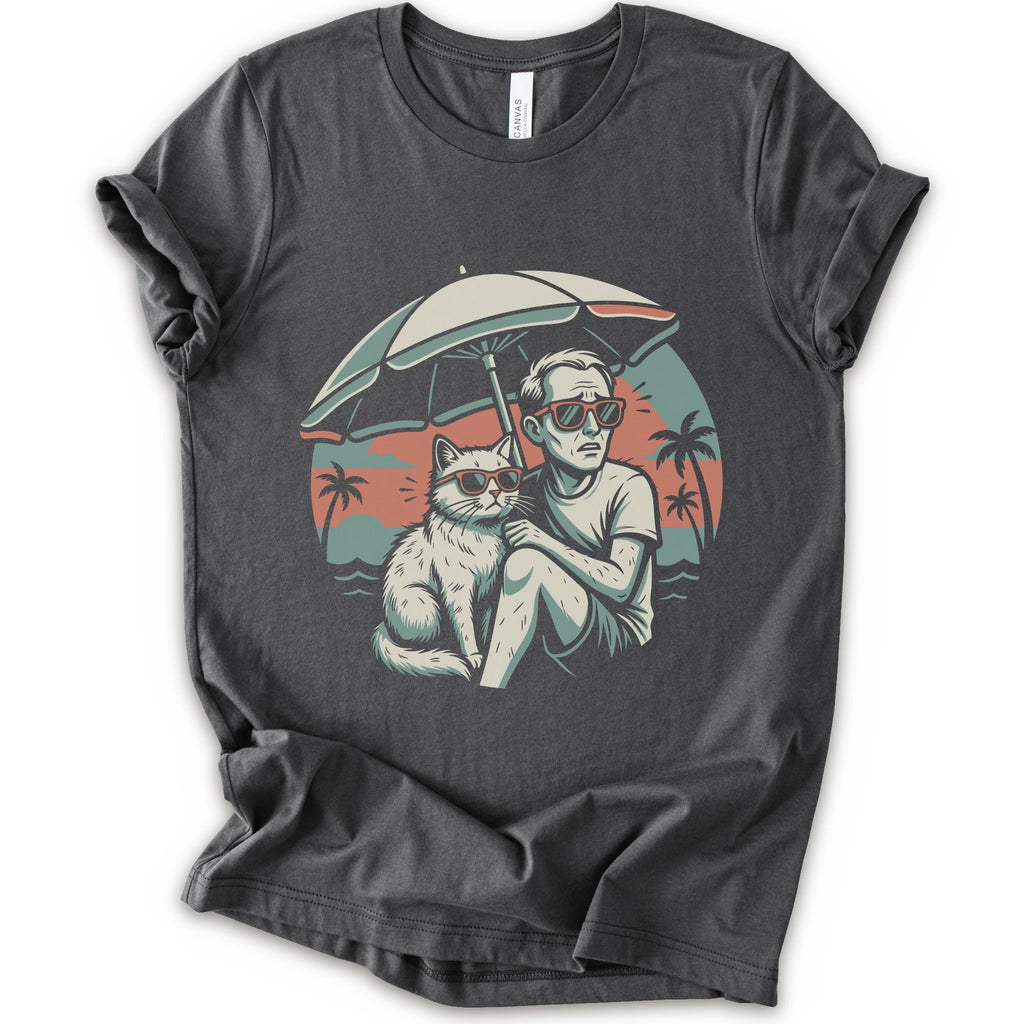 A asphalt short-sleeve crewneck t-shirt with a vintage-style graphic print of a man and a cat sitting under a beach umbrella on a sunset beach.