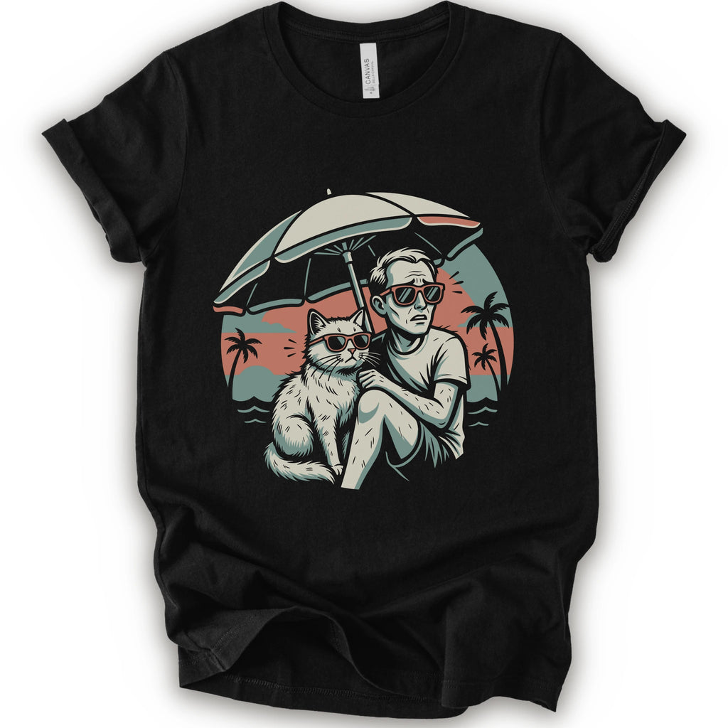 A black short-sleeve crewneck t-shirt with a vintage-style graphic print of a man and a cat sitting under a beach umbrella on a sunset beach.