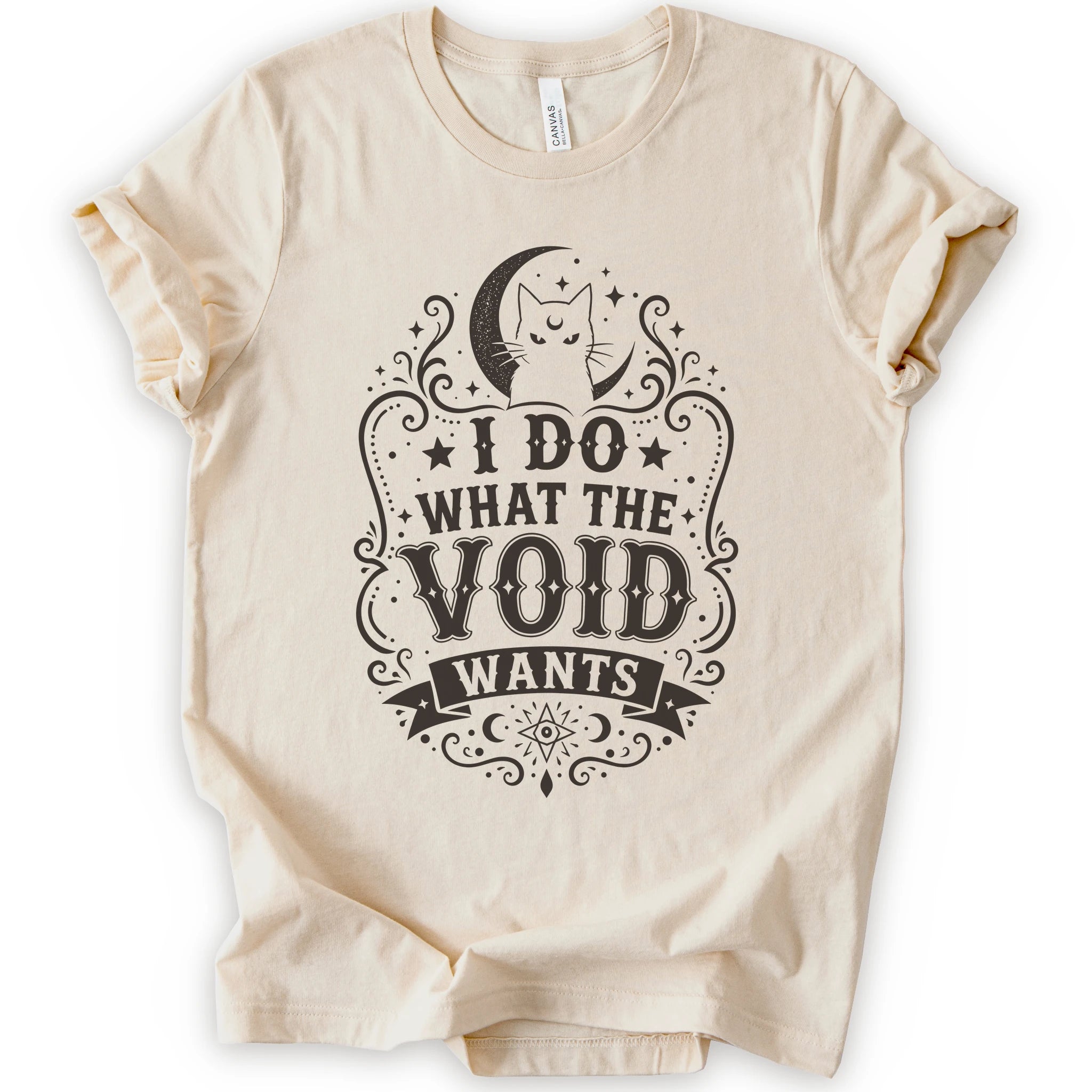 Natural graphic t-shirt with a vintage-style brown graphic on the front. The graphic features a crescent moon, cat silhouette, stars, and the text 'I DO WHAT THE VOID WANTS'.