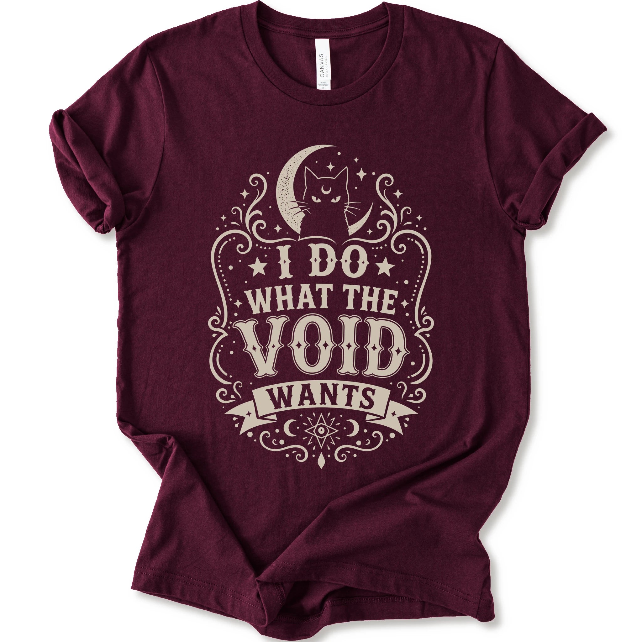 Maroon graphic t-shirt with a vintage-style cream graphic on the front. The graphic features a crescent moon, cat silhouette, stars, and the text 'I DO WHAT THE VOID WANTS'.