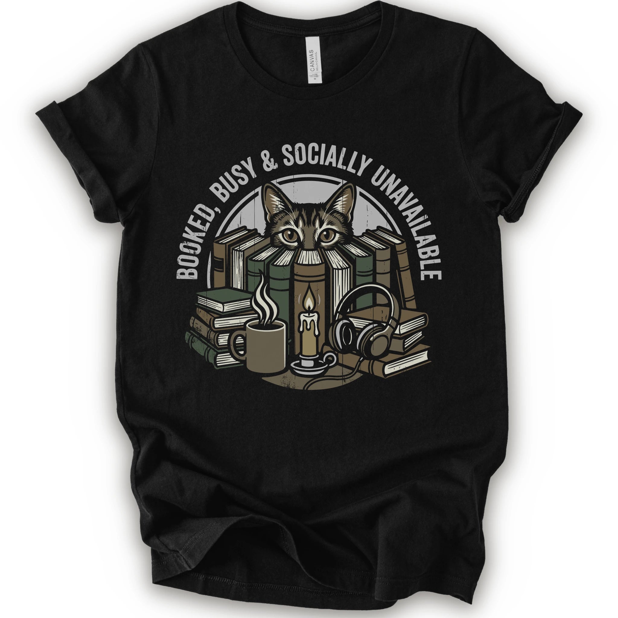 A black short-sleeve crewneck t-shirt with a graphic print of a cat peeking out from stacked books, headphones, and a mug, with the text 'BOOKED BUSY & SOCIALLY UNAVAILABLE' arched above.