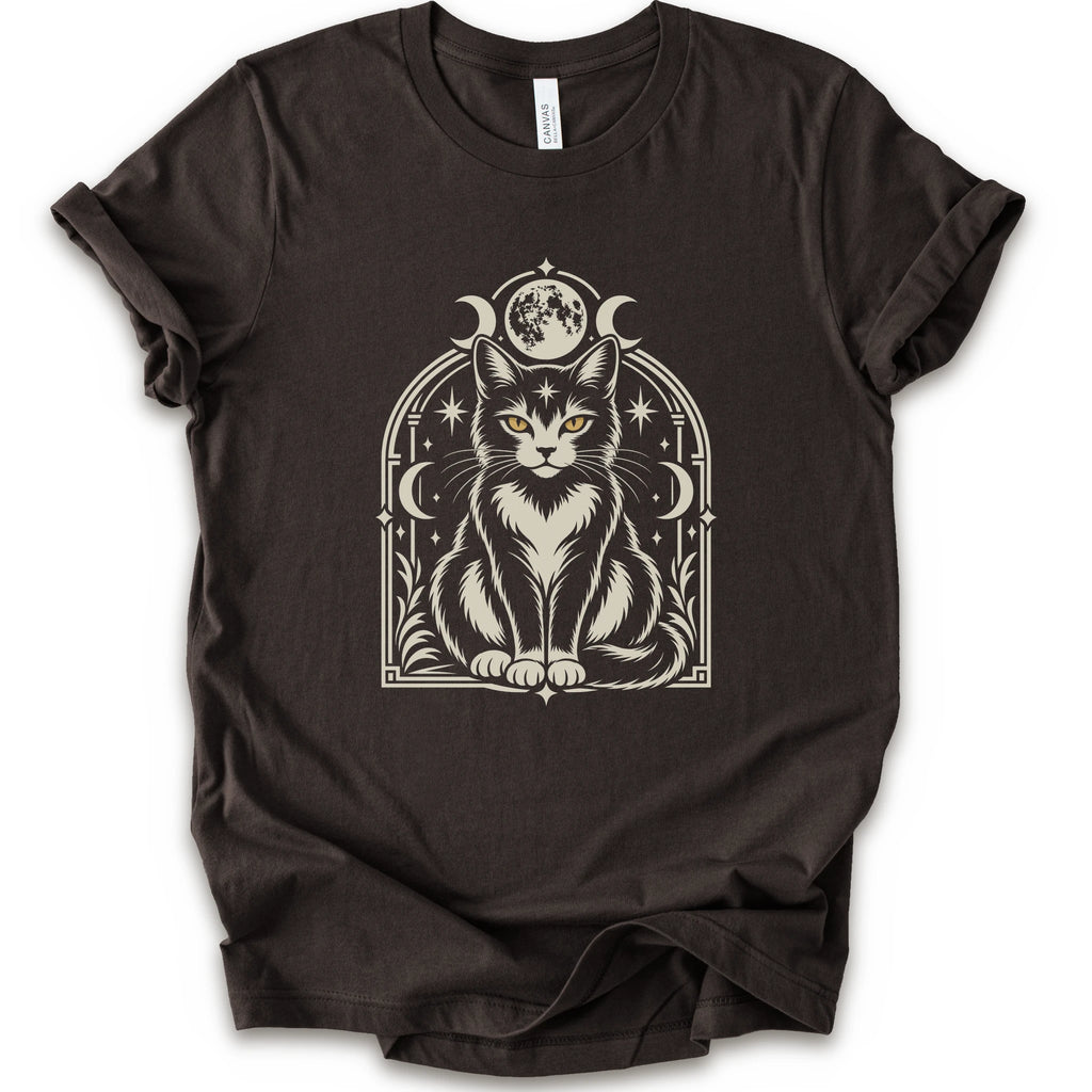 A brown short-sleeve crewneck t-shirt featuring a detailed graphic of a black and white cat with yellow eyes, framed by crescent moons and stars.