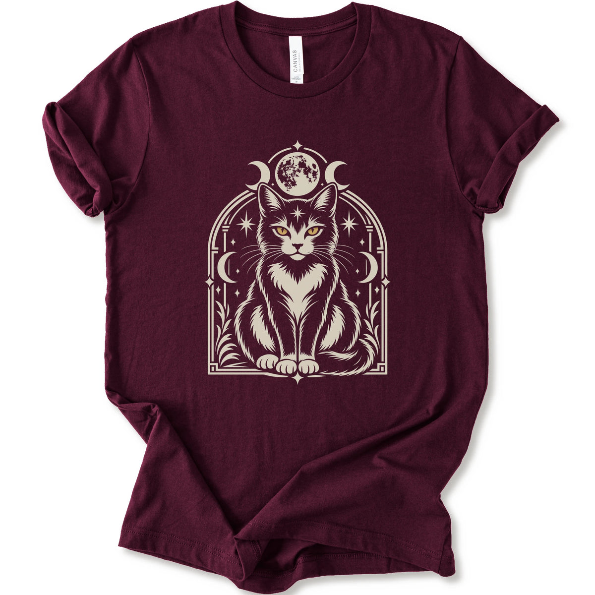 A maroon short-sleeve crewneck t-shirt featuring a detailed graphic of a black and white cat with yellow eyes, framed by crescent moons and stars.