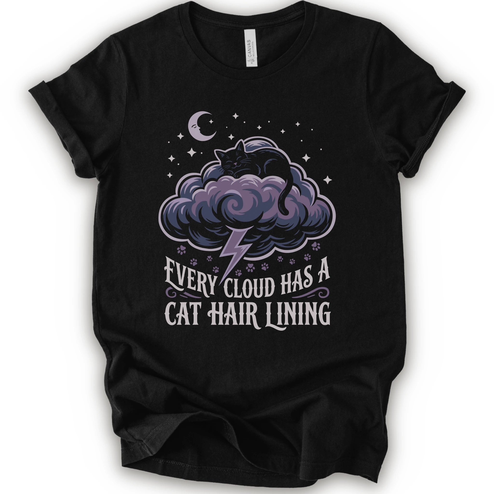 A black short-sleeve crewneck t-shirt with a graphic print of a black cat sitting on a purple cloud with a lightning bolt, under a crescent moon and stars. Below the graphic, the text reads 'EVERY CLOUD HAS A CAT HAIR LINING'.