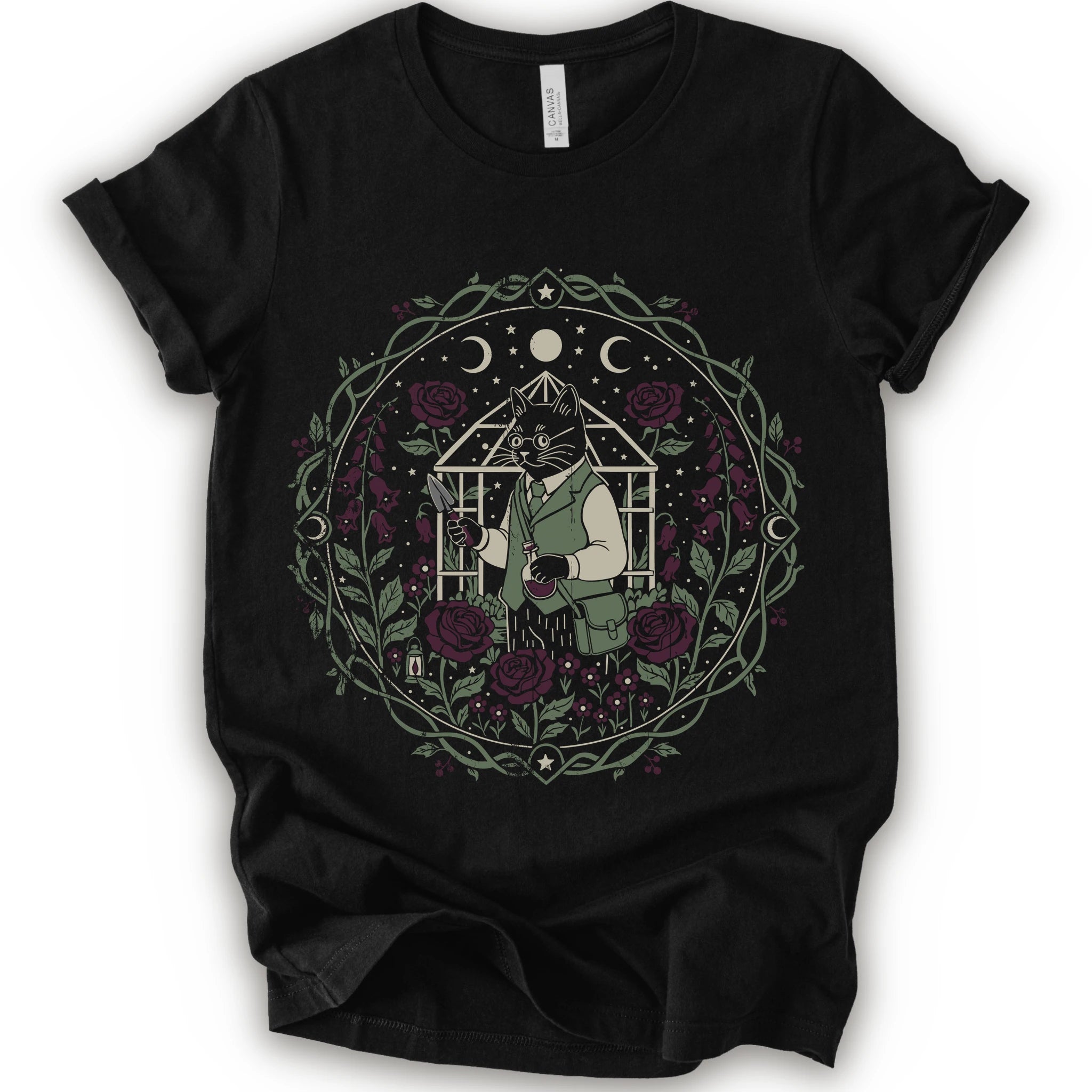 A black short-sleeve crewneck t-shirt featuring a detailed dark botanical cat graphic with a bespectacled black cat gardener, greenhouse, roses, stars, and crescent moons.