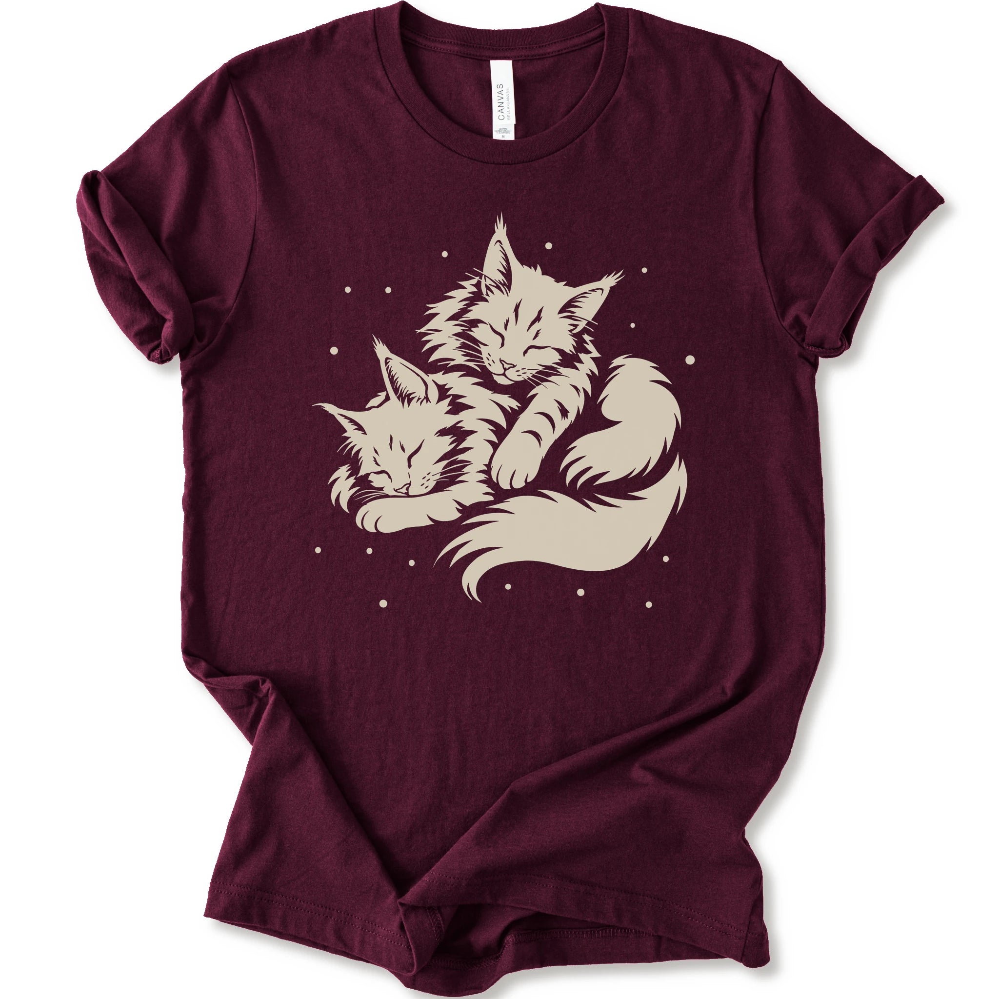 A maroon short-sleeve crewneck t-shirt featuring a cream-colored graphic of two sleeping fluffy kittens nestled together on a white background.