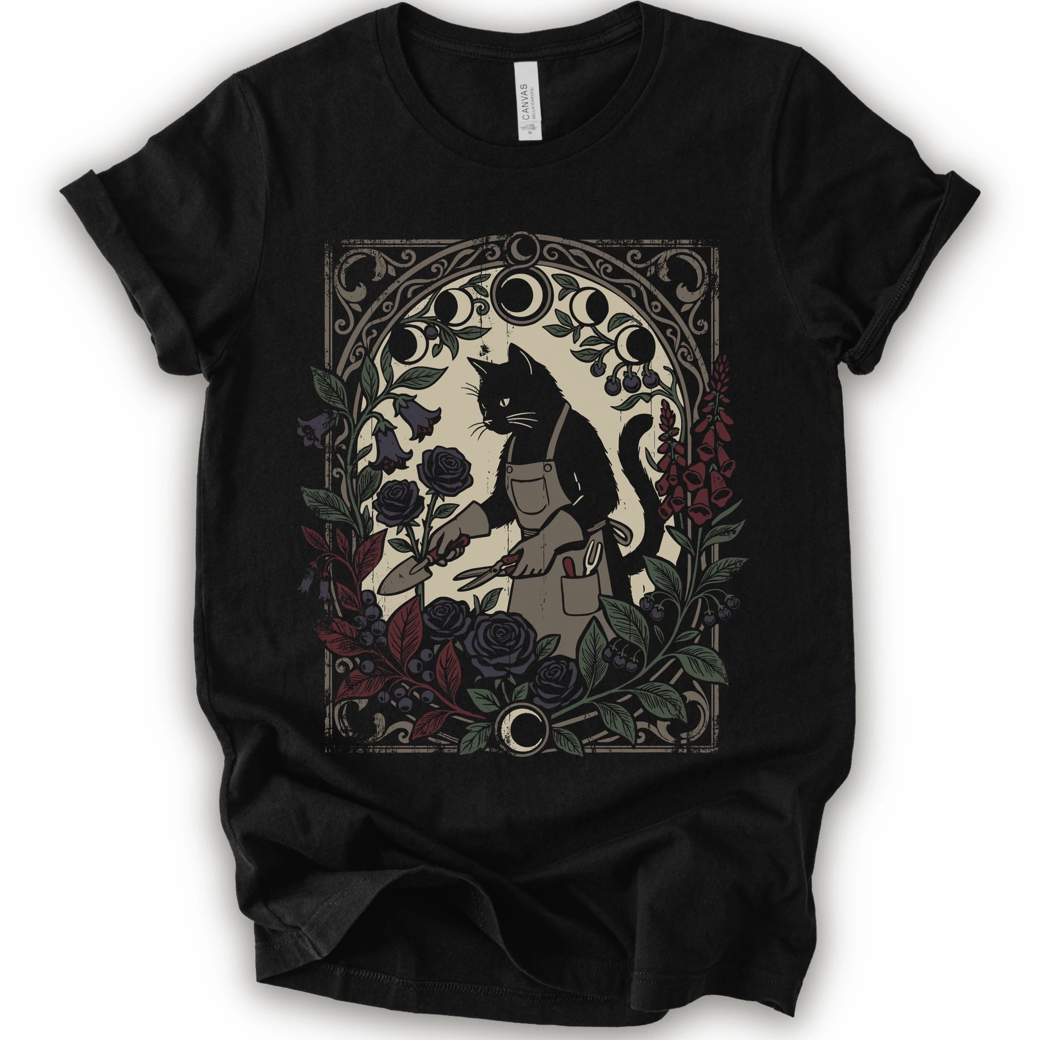 A black short-sleeve crewneck T-shirt with a dark botanical black cat gardener graphic, moon phases, roses, and ornate framing.