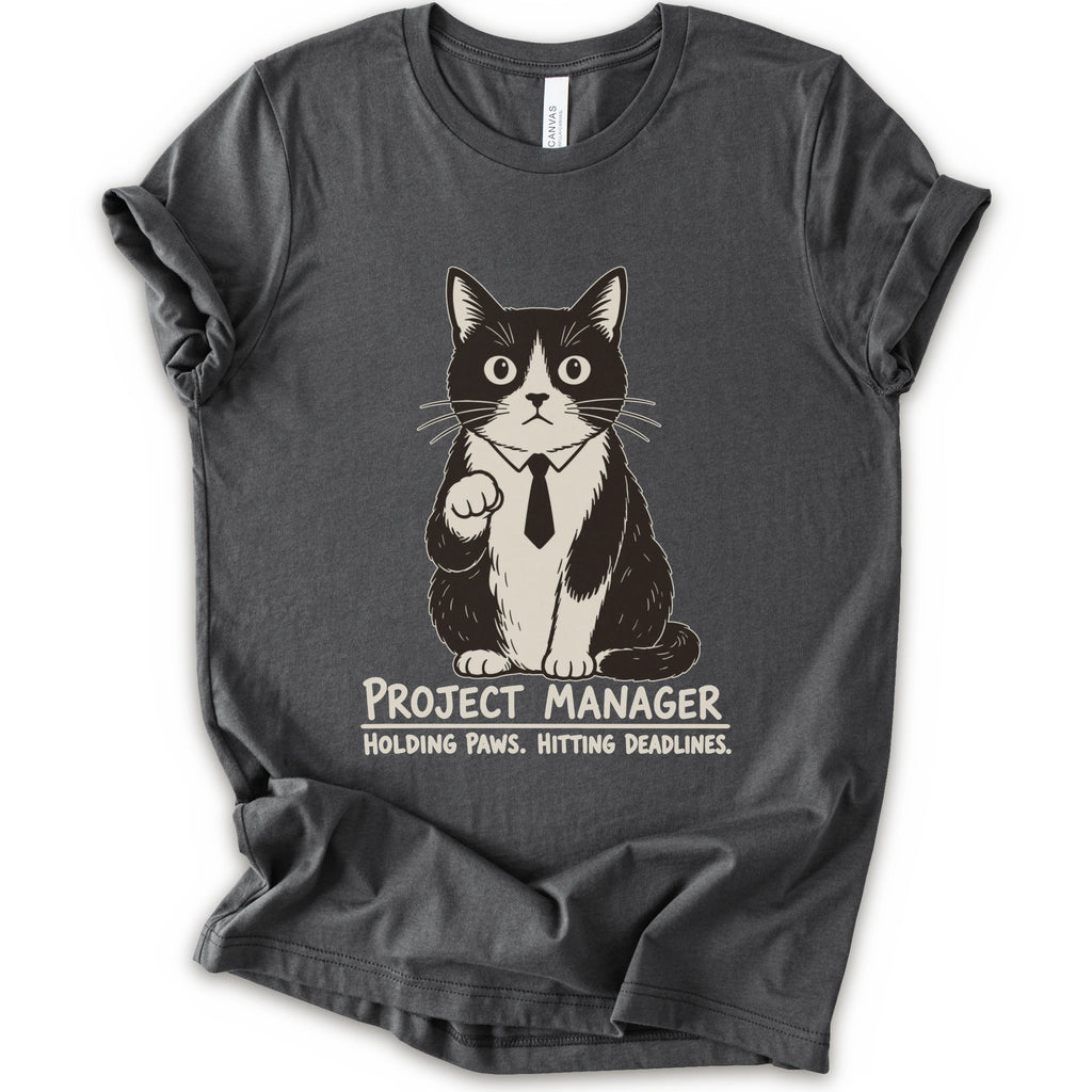 An asphalt short-sleeve crewneck t-shirt featuring a graphic of a black and white cat wearing a tie with the text 'PROJECT MANAGER HOLDING PAWS. HITTING DEADLINES.
