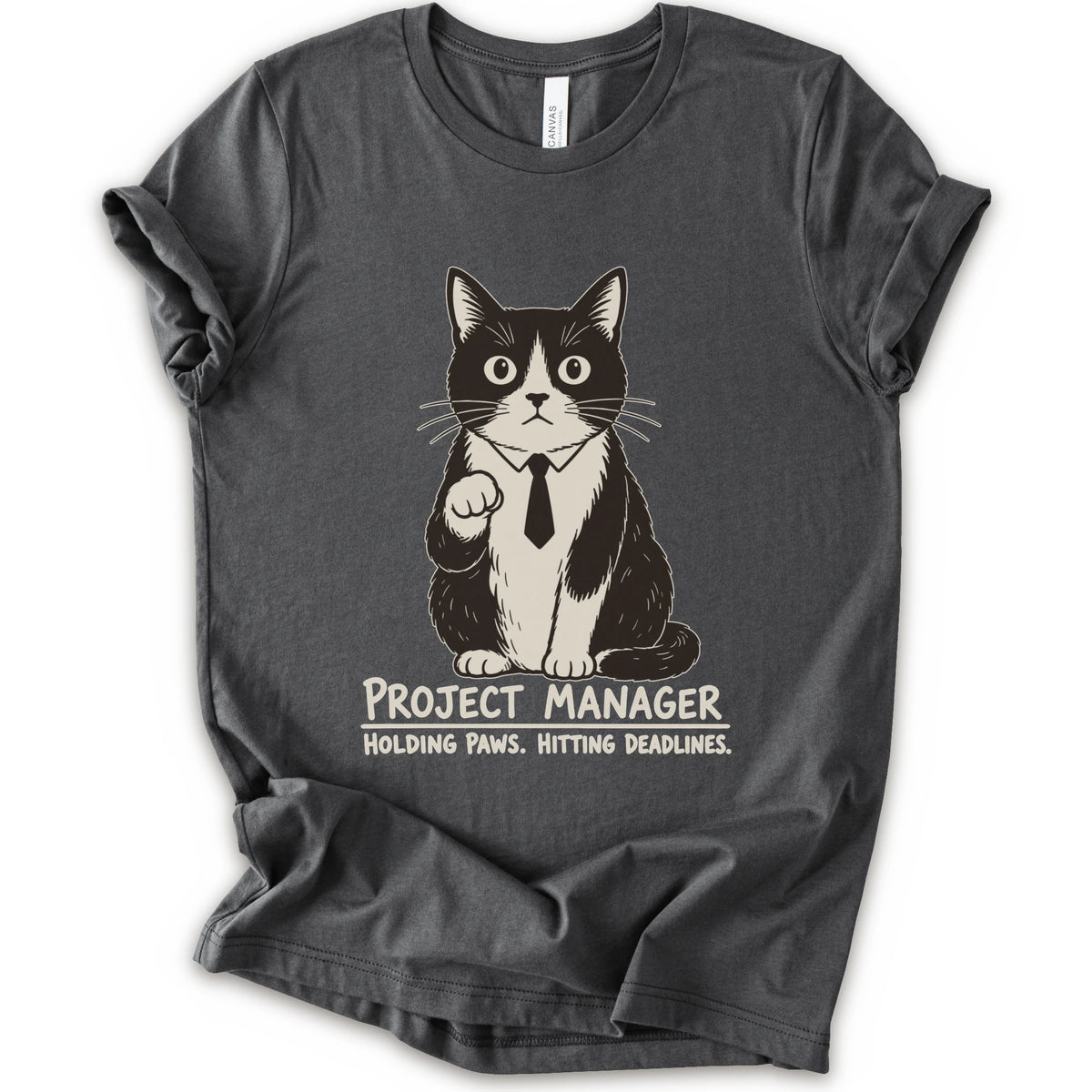 An asphalt short-sleeve crewneck t-shirt featuring a graphic of a black and white cat wearing a tie with the text 'PROJECT MANAGER HOLDING PAWS. HITTING DEADLINES.