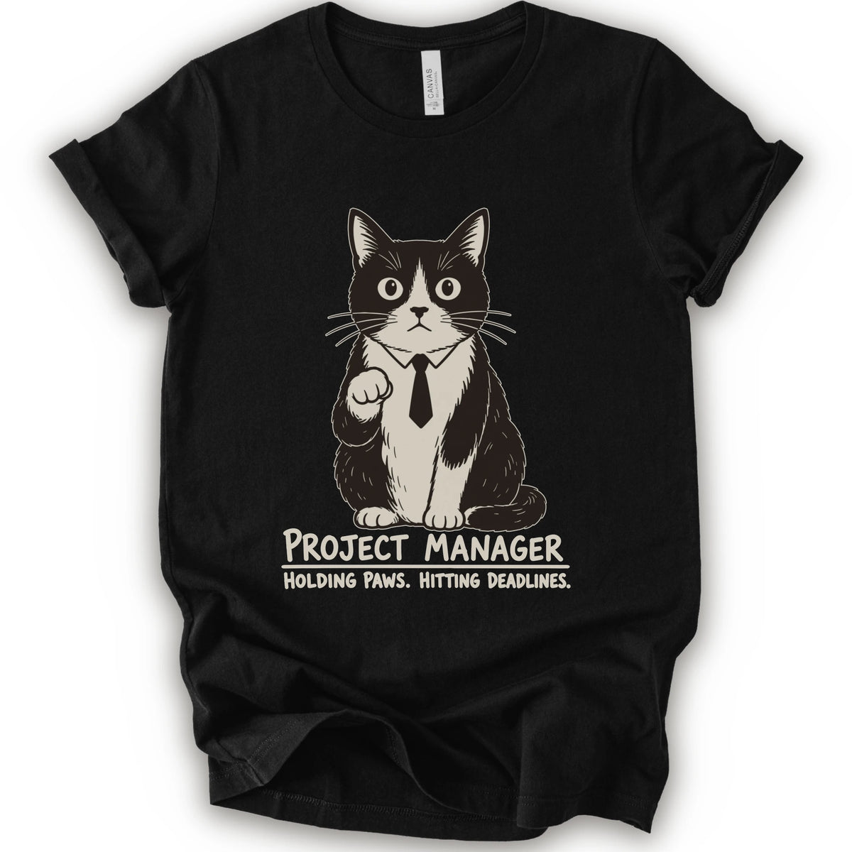 A black short-sleeve crewneck t-shirt featuring a graphic of a black and white cat wearing a tie with the text 'PROJECT MANAGER HOLDING PAWS. HITTING DEADLINES.