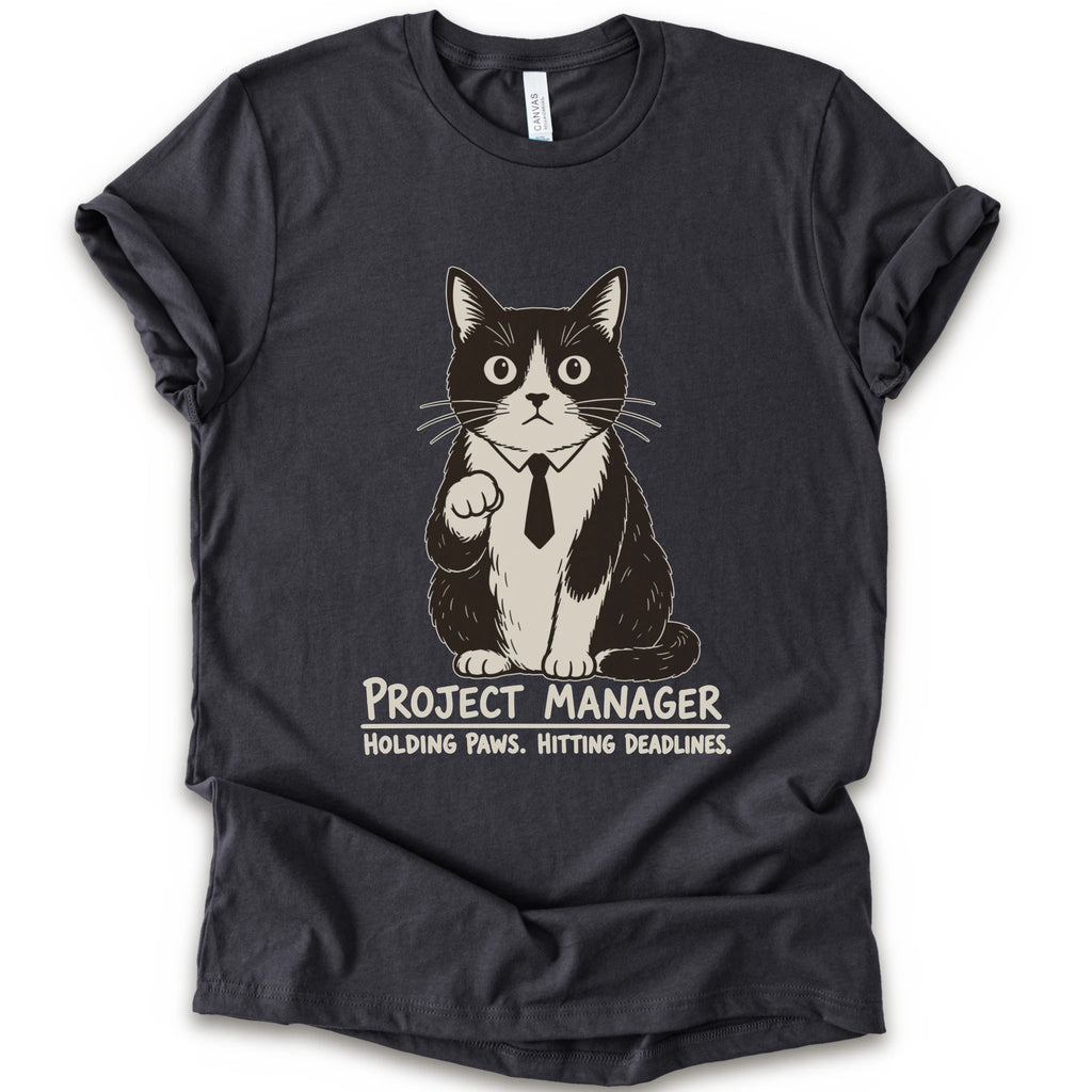 A dark grey short-sleeve crewneck t-shirt featuring a graphic of a black and white cat wearing a tie with the text 'PROJECT MANAGER HOLDING PAWS. HITTING DEADLINES.
