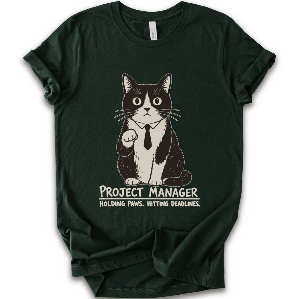 A forest short-sleeve crewneck t-shirt featuring a graphic of a black and white cat wearing a tie with the text 'PROJECT MANAGER HOLDING PAWS. HITTING DEADLINES.