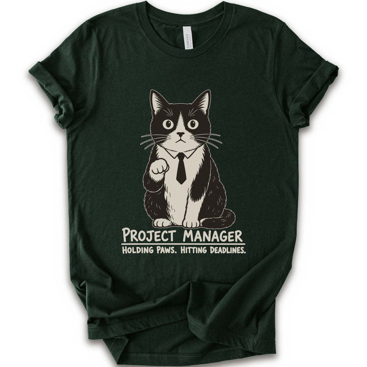 A forest short-sleeve crewneck t-shirt featuring a graphic of a black and white cat wearing a tie with the text 'PROJECT MANAGER HOLDING PAWS. HITTING DEADLINES.