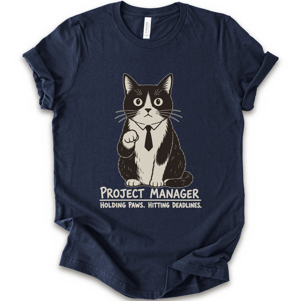 A navy short-sleeve crewneck t-shirt featuring a graphic of a black and white cat wearing a tie with the text 'PROJECT MANAGER HOLDING PAWS. HITTING DEADLINES.