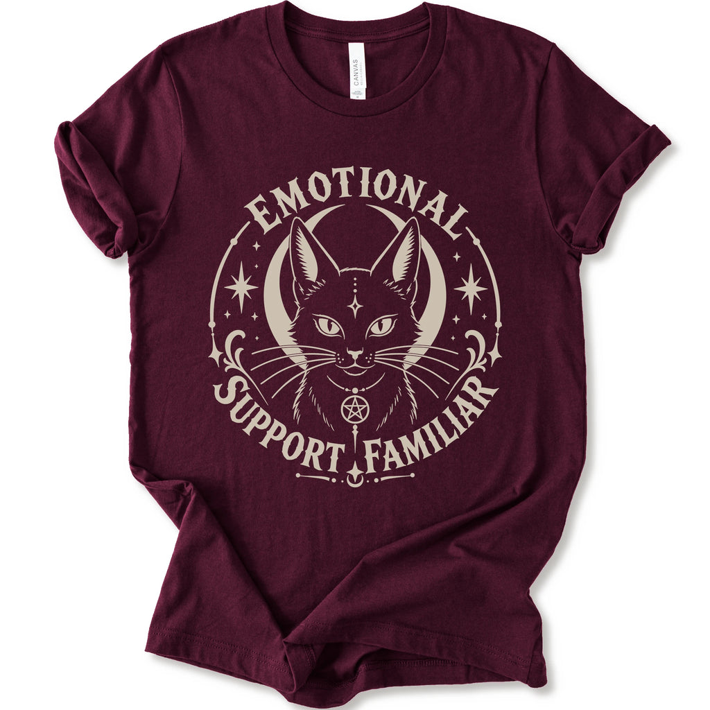 A maroon short-sleeve crewneck t-shirt with a distressed cream graphic of a cat's face inside a circle, surrounded by the text 'EMOTIONAL SUPPORT FAMILIAR'.