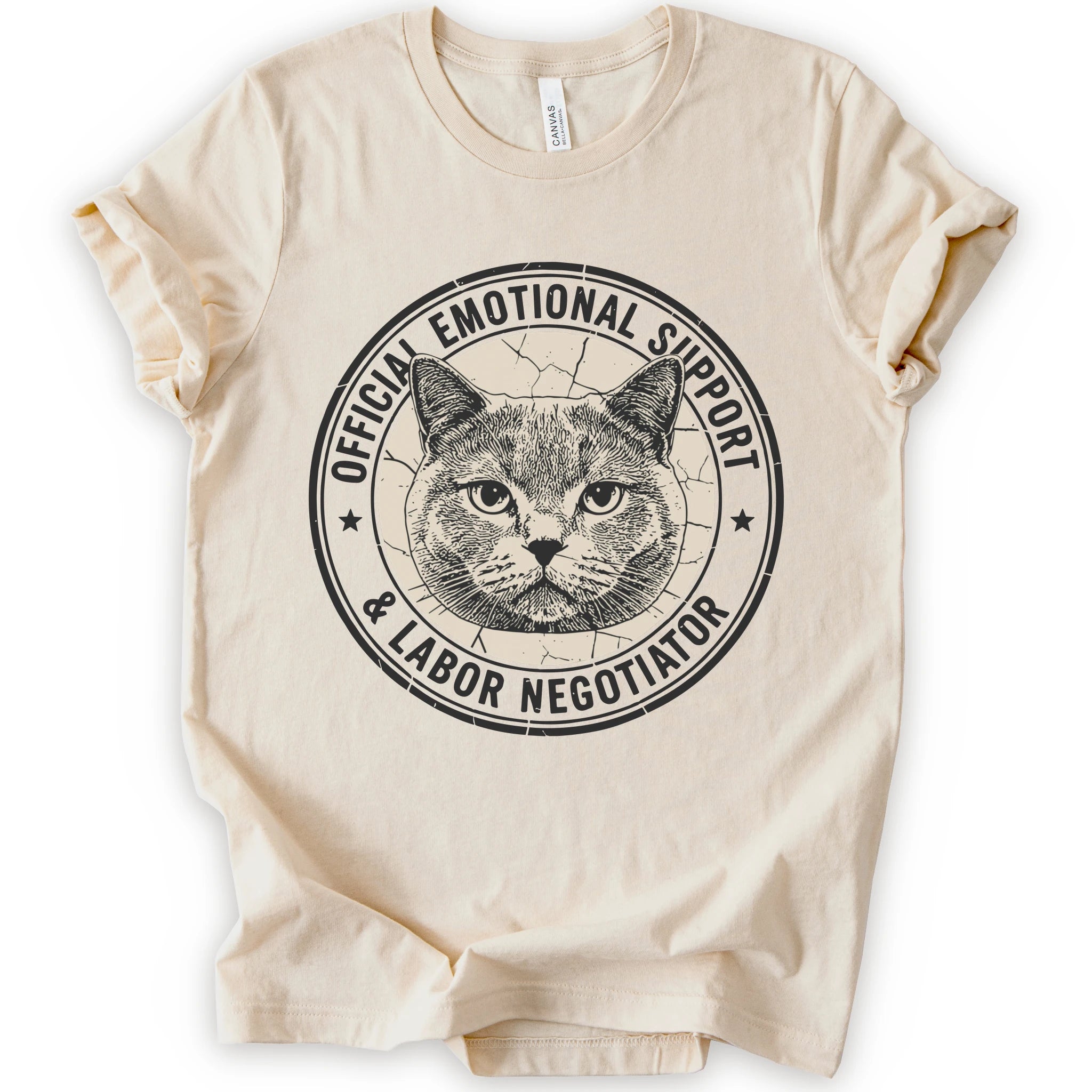 A natural short-sleeve crewneck t-shirt with a distressed circular graphic on the chest featuring a cat's face and the text 'OFFICIAL EMOTIONAL SUPPORT & LABOR NEGOTIATOR'.