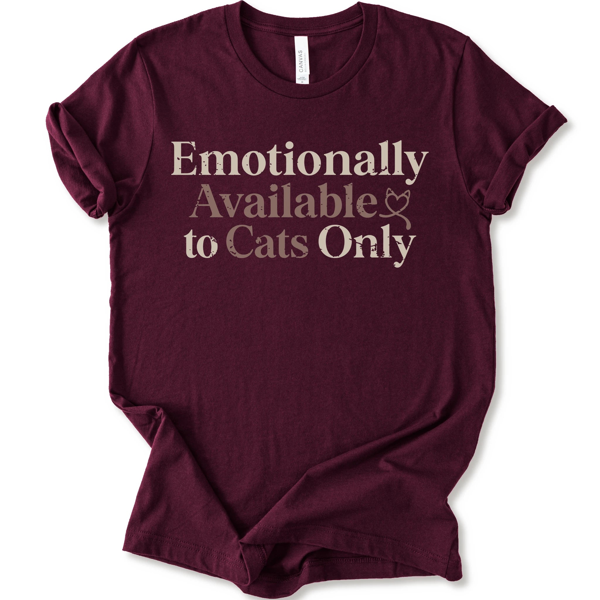 A maroon short-sleeve crewneck t-shirt with the text 'Emotionally Available to Cats Only' printed on the front in a beige and dusty rose serif font.