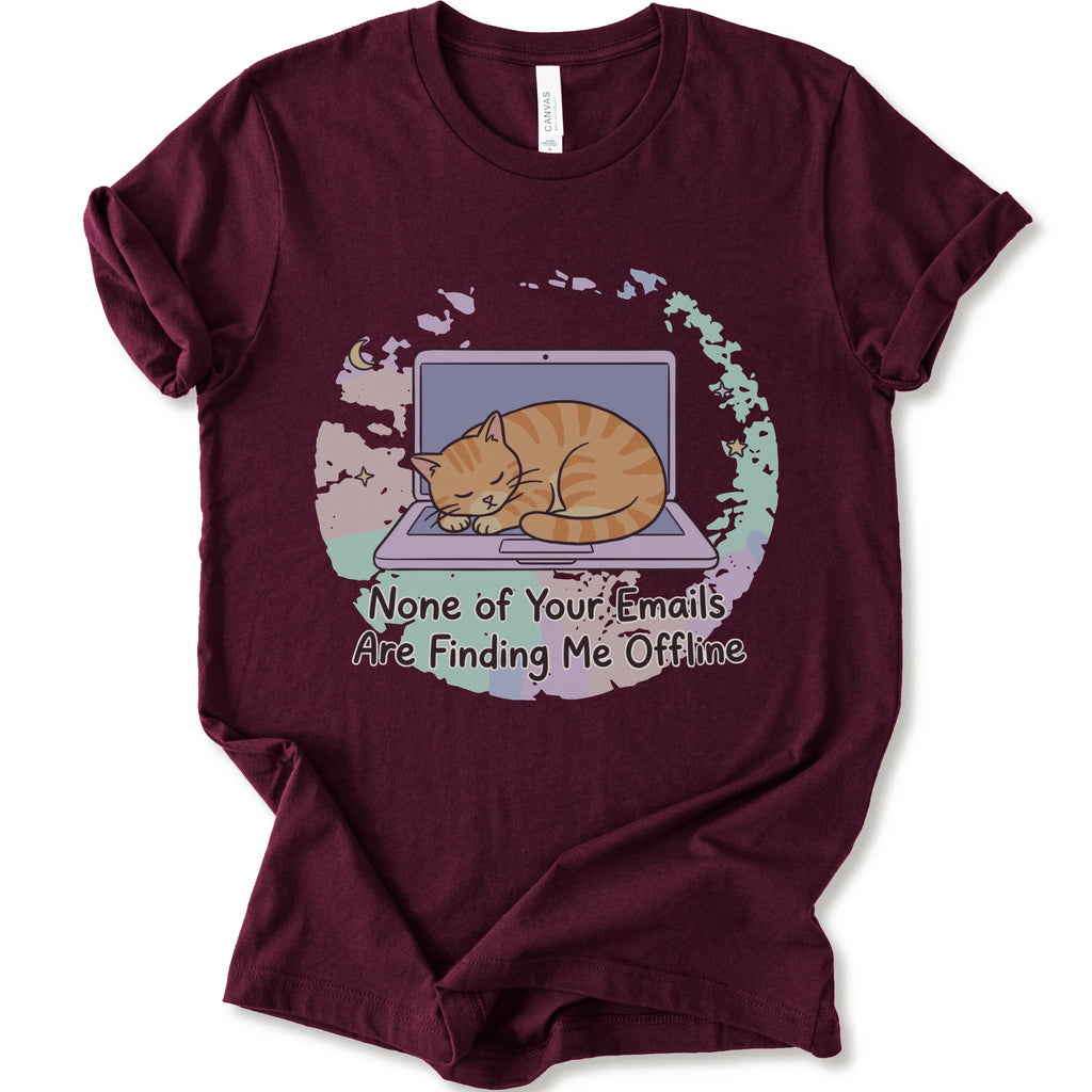 A maroon short-sleeve graphic t-shirt featuring an illustration of an orange tabby cat sleeping on a laptop with the text 'None of Your Emails Are Finding Me Offline' underneath.