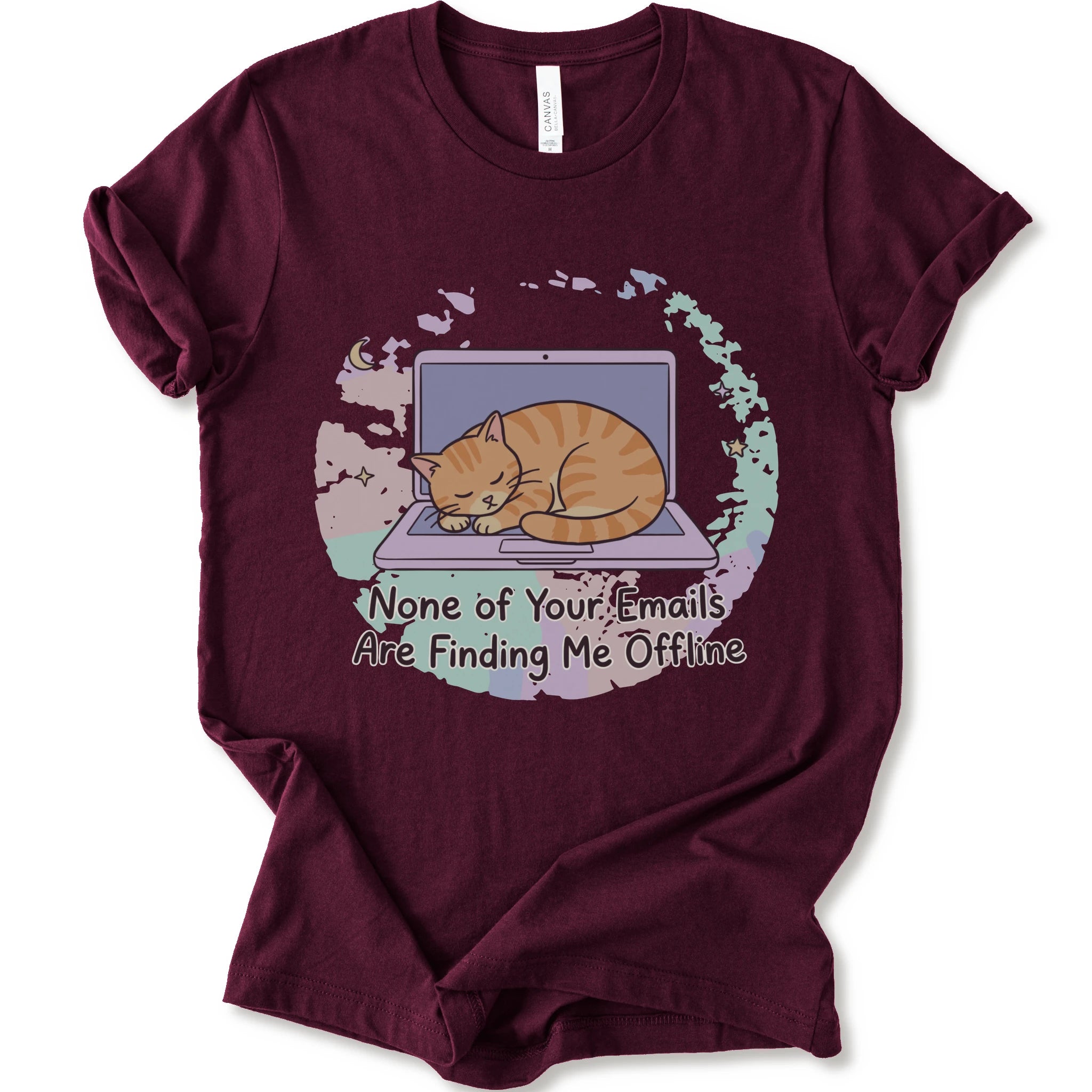 A maroon short-sleeve graphic t-shirt featuring an illustration of an orange tabby cat sleeping on a laptop with the text 'None of Your Emails Are Finding Me Offline' underneath.