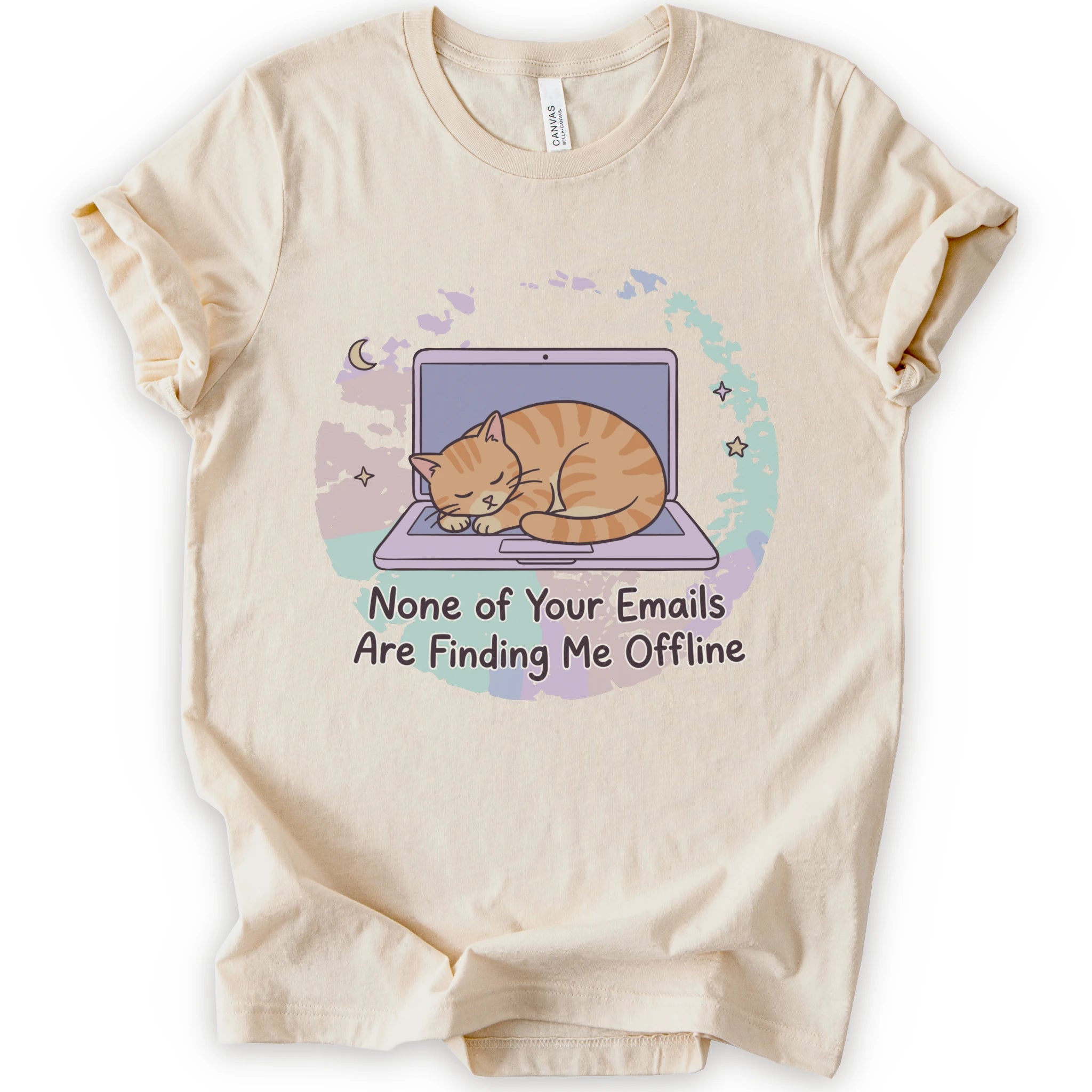 A natural short-sleeve graphic t-shirt featuring an illustration of an orange tabby cat sleeping on a laptop with the text 'None of Your Emails Are Finding Me Offline' underneath.