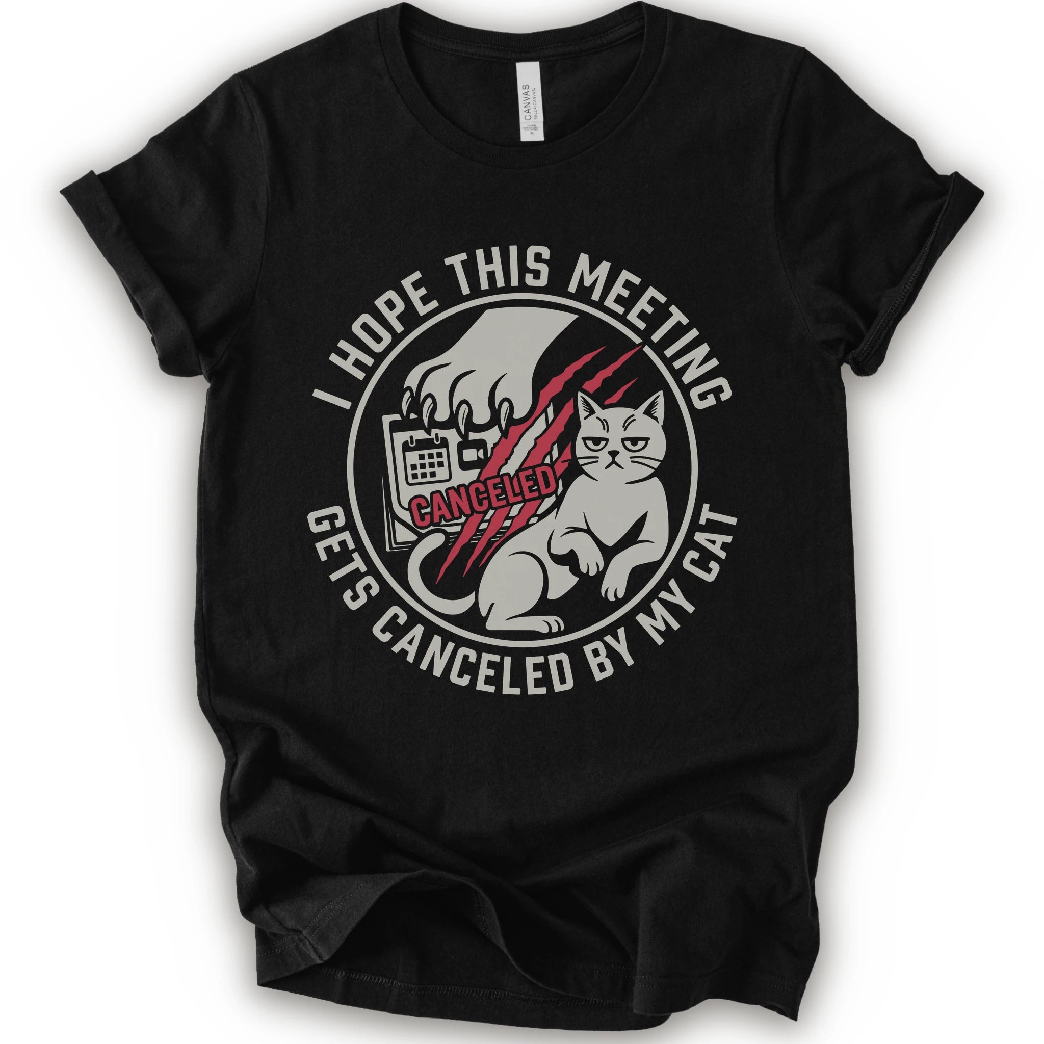 A black short-sleeve crewneck t-shirt with a circular graphic on the front. The graphic features a white cat, a hand scratching, and the text 'I HOPE THIS MEETING GETS CANCELLED BY MY CAT' in white, with 'CANCELLED' written in red script.
