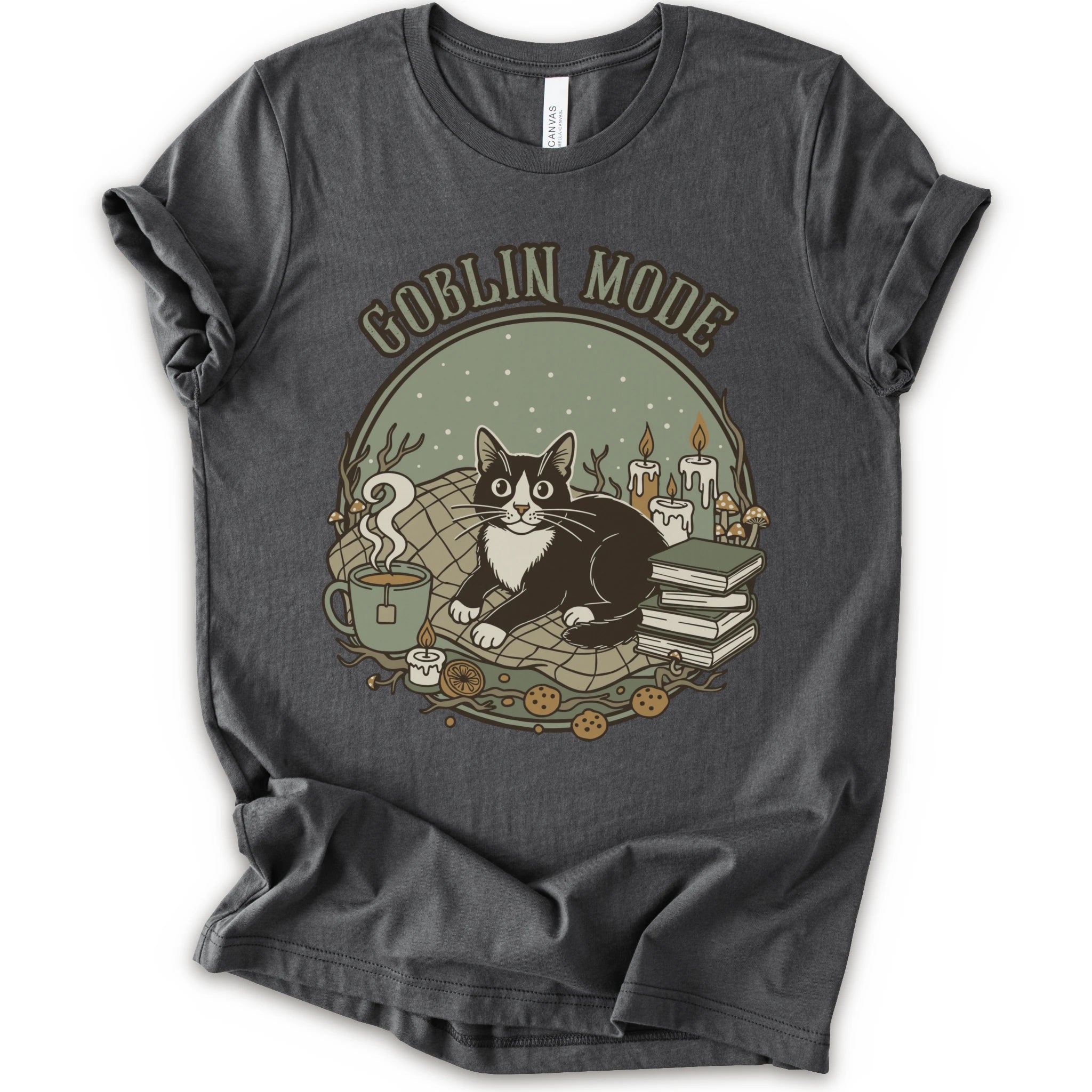 A asphalt short-sleeve crewneck t-shirt with a cozy 'Goblin Mode' graphic print featuring a black and white cat, candles, books, and a mug.