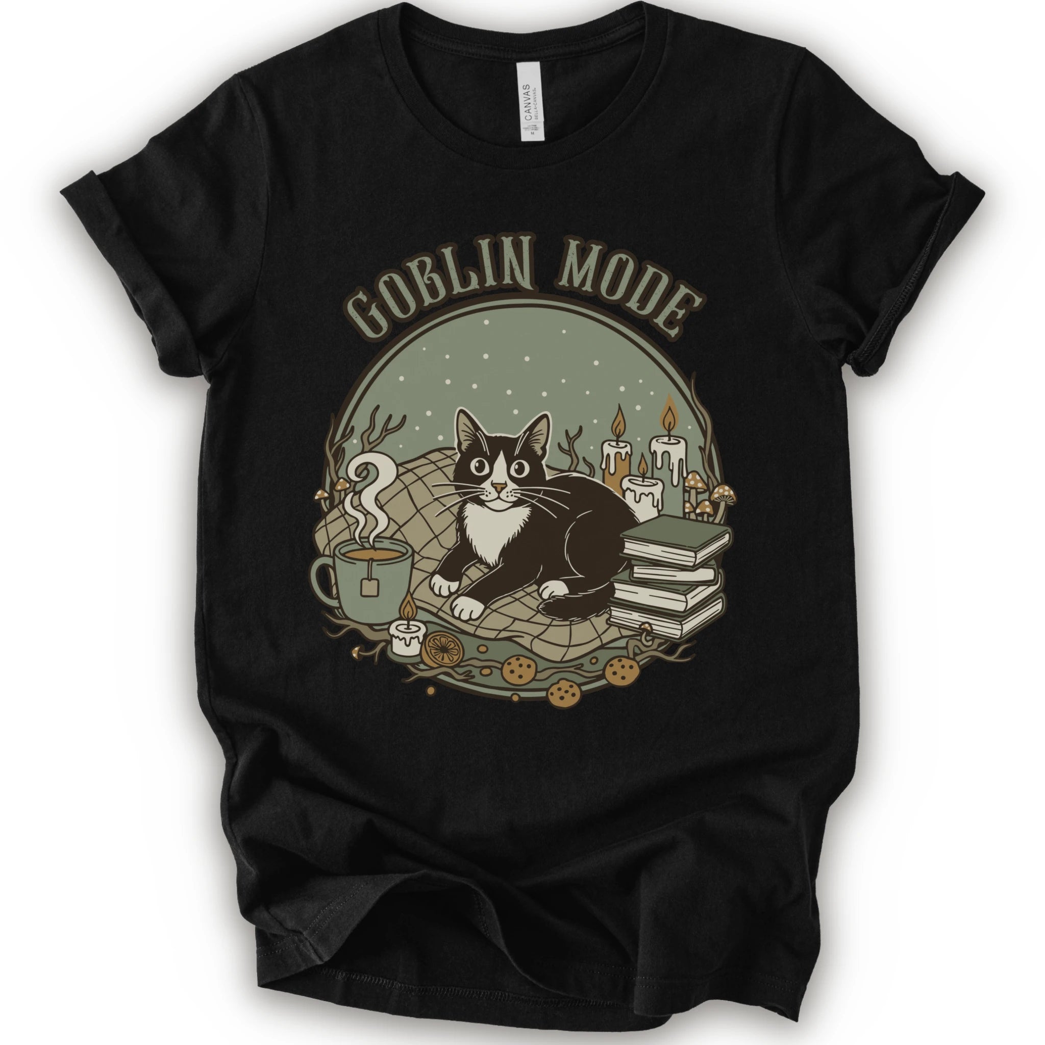 A black short-sleeve crewneck t-shirt with a cozy 'Goblin Mode' graphic print featuring a black and white cat, candles, books, and a mug.