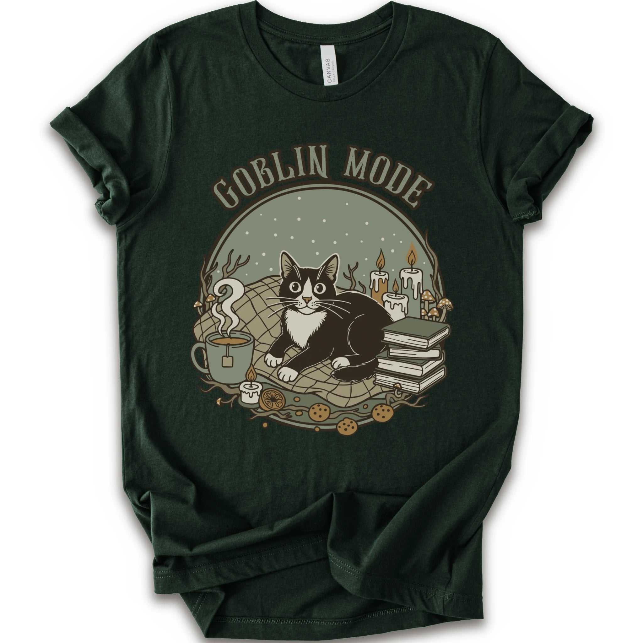 A forest short-sleeve crewneck t-shirt with a cozy 'Goblin Mode' graphic print featuring a black and white cat, candles, books, and a mug.
