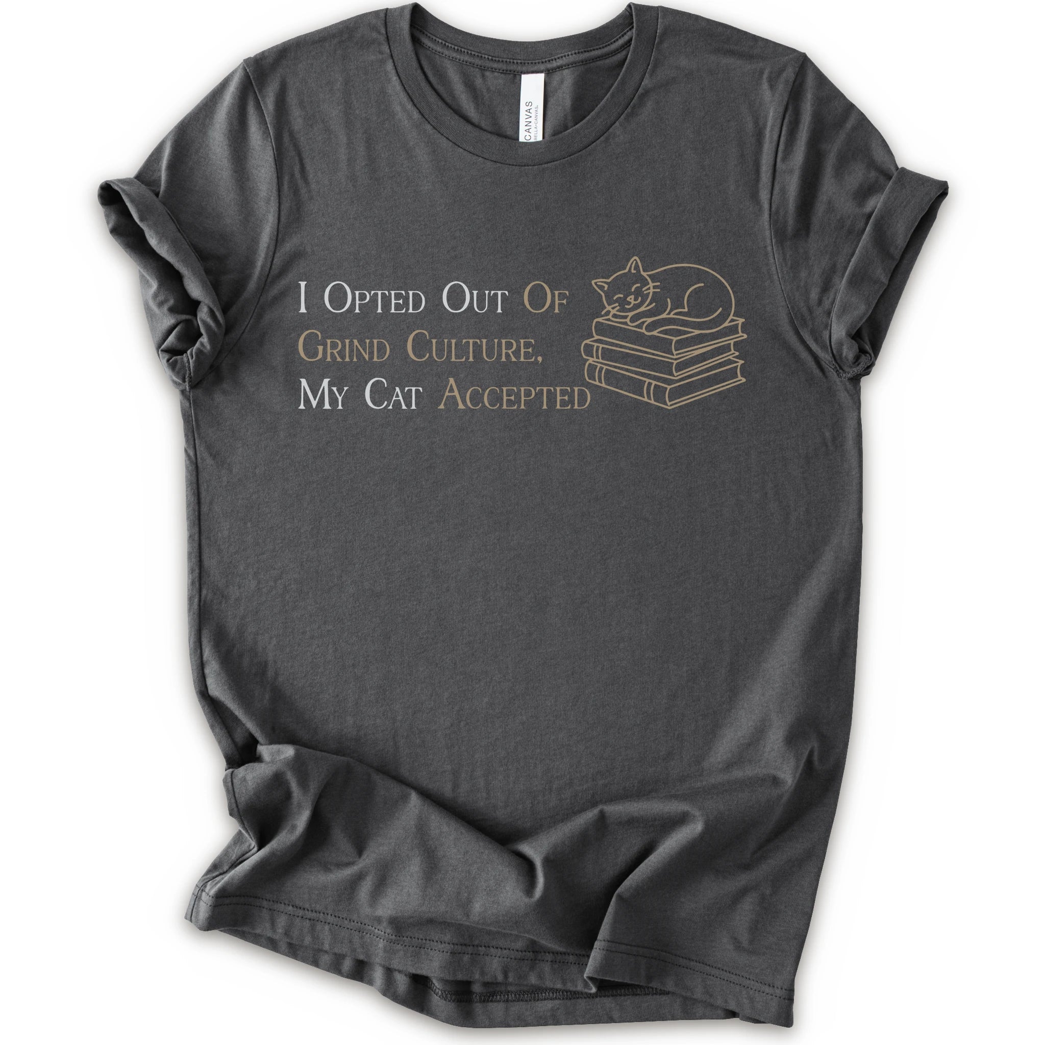 A asphalt short-sleeve crew neck T-shirt with "I Opted Out Of Grind Culture, My Cat Accepted" lettering beside a sleeping cat on stacked books