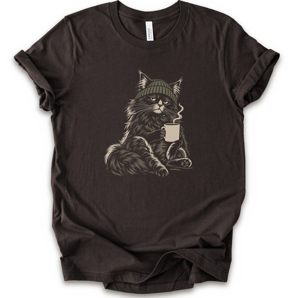A brown short-sleeve t-shirt with a graphic of a fluffy cat wearing a green beanie and holding a mug, displayed.