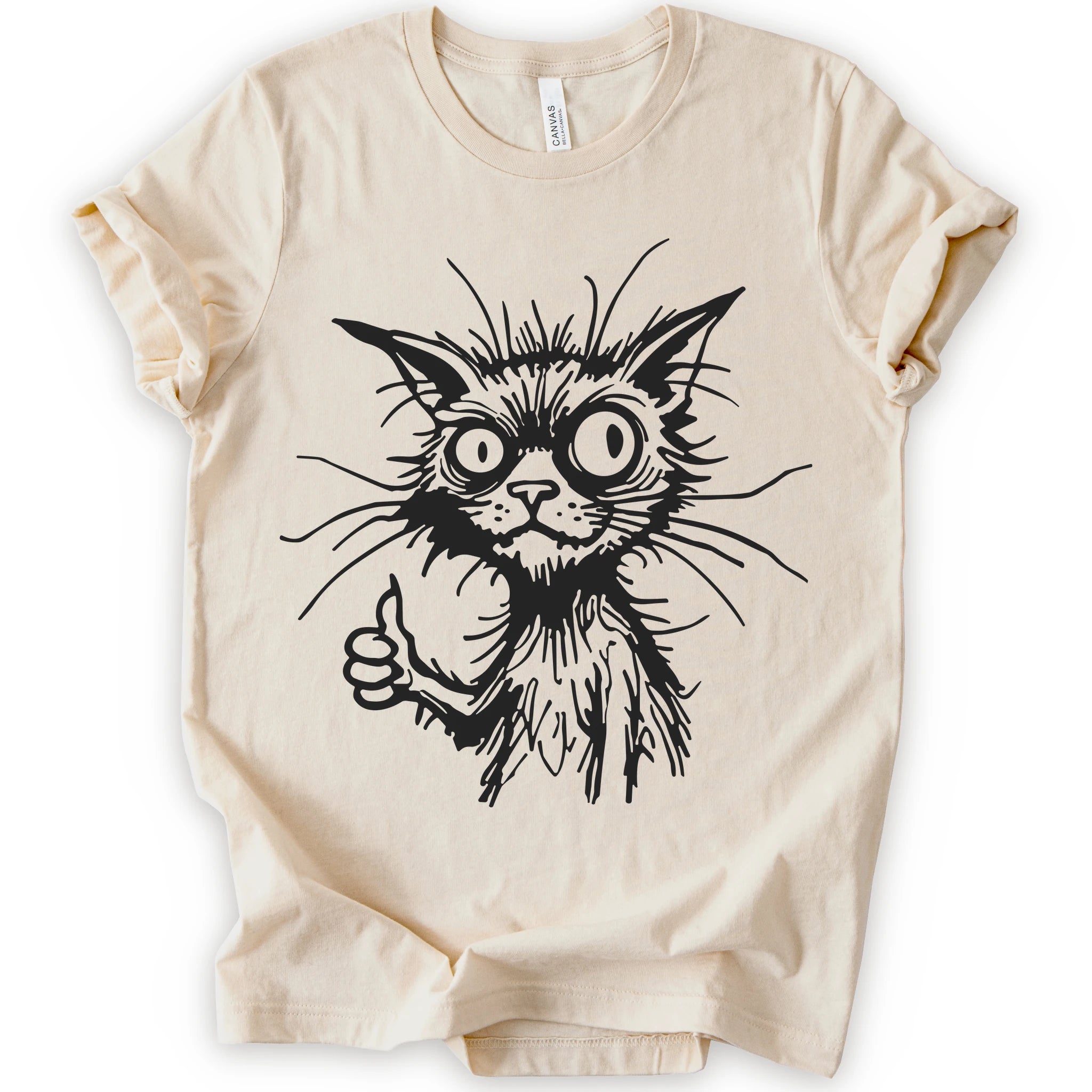A natural short-sleeve crewneck t-shirt featuring a black graphic illustration of a wild-eyed cat giving a thumbs-up, displayed on a clean white background.