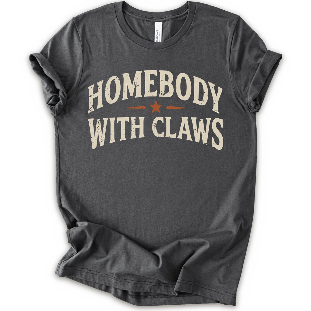 A asphalt short-sleeve t-shirt with a distressed graphic reading 'HOMEBODY WITH CLAWS' in cream lettering and a small orange star accent