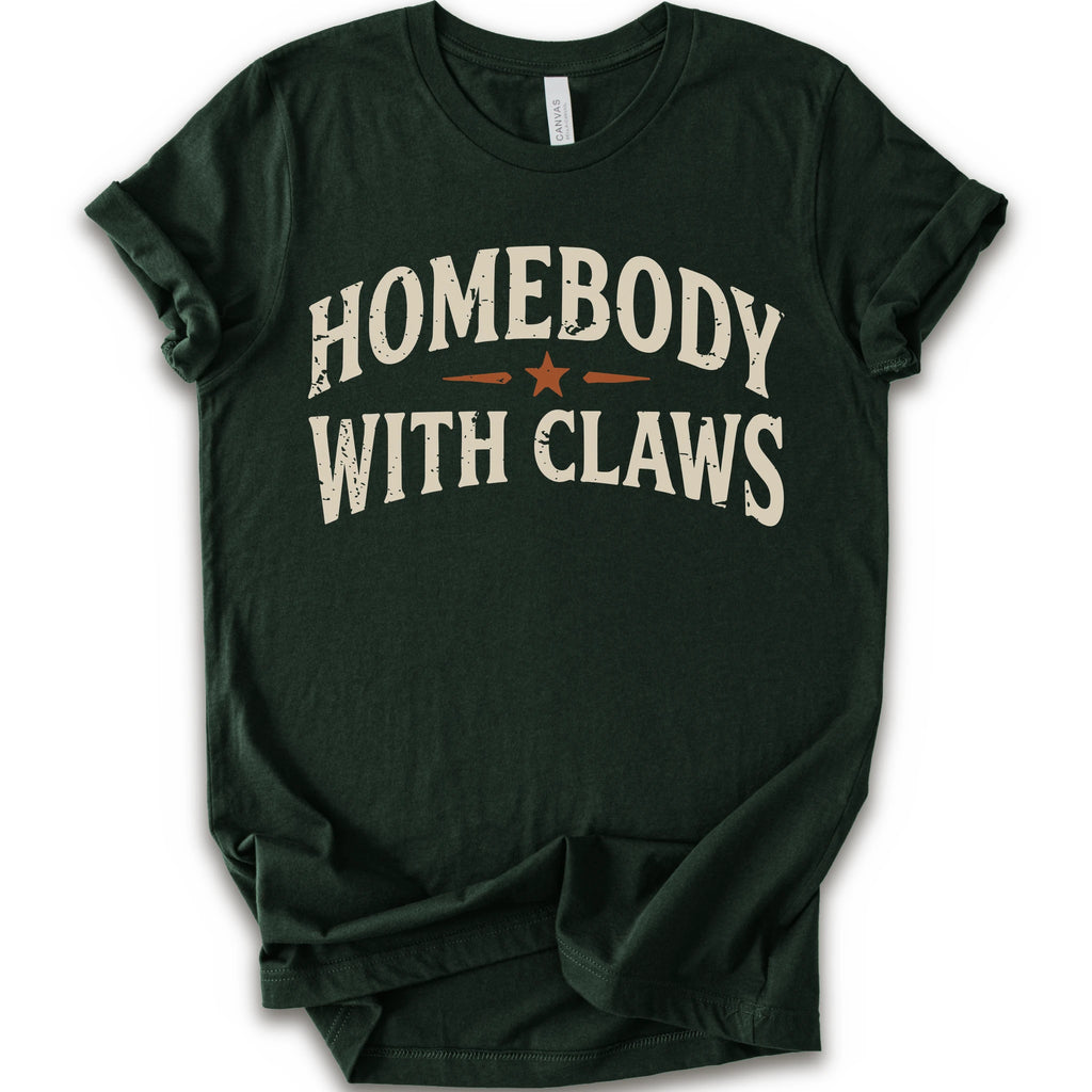 A forest short-sleeve t-shirt with a distressed graphic reading 'HOMEBODY WITH CLAWS' in cream lettering and a small orange star accent