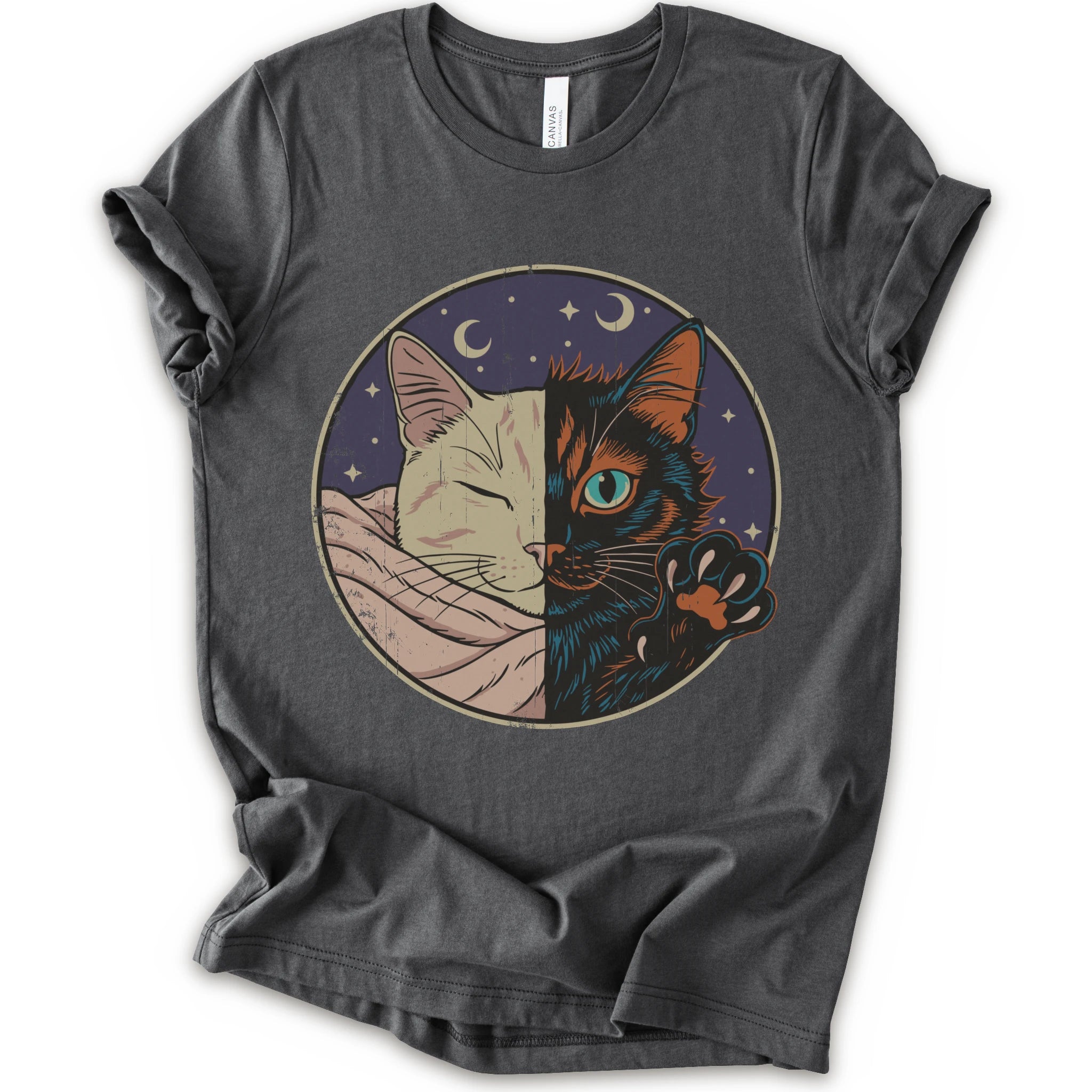 A asphalt short-sleeve crewneck t-shirt featuring a circular graphic print of a split cat design, showing one half as a sleeping cream-colored cat wrapped in a blanket and the other half as a dark black cat with a glowing blue eye and paw resting on its head.