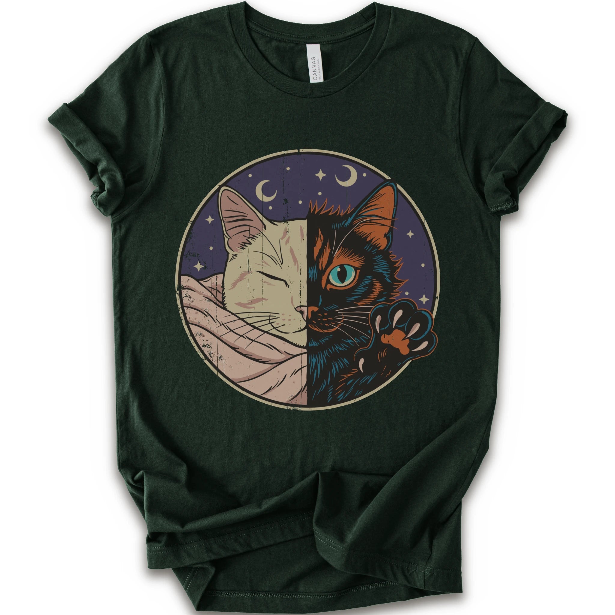A forest short-sleeve crewneck t-shirt featuring a circular graphic print of a split cat design, showing one half as a sleeping cream-colored cat wrapped in a blanket and the other half as a dark black cat with a glowing blue eye and paw resting on its head.