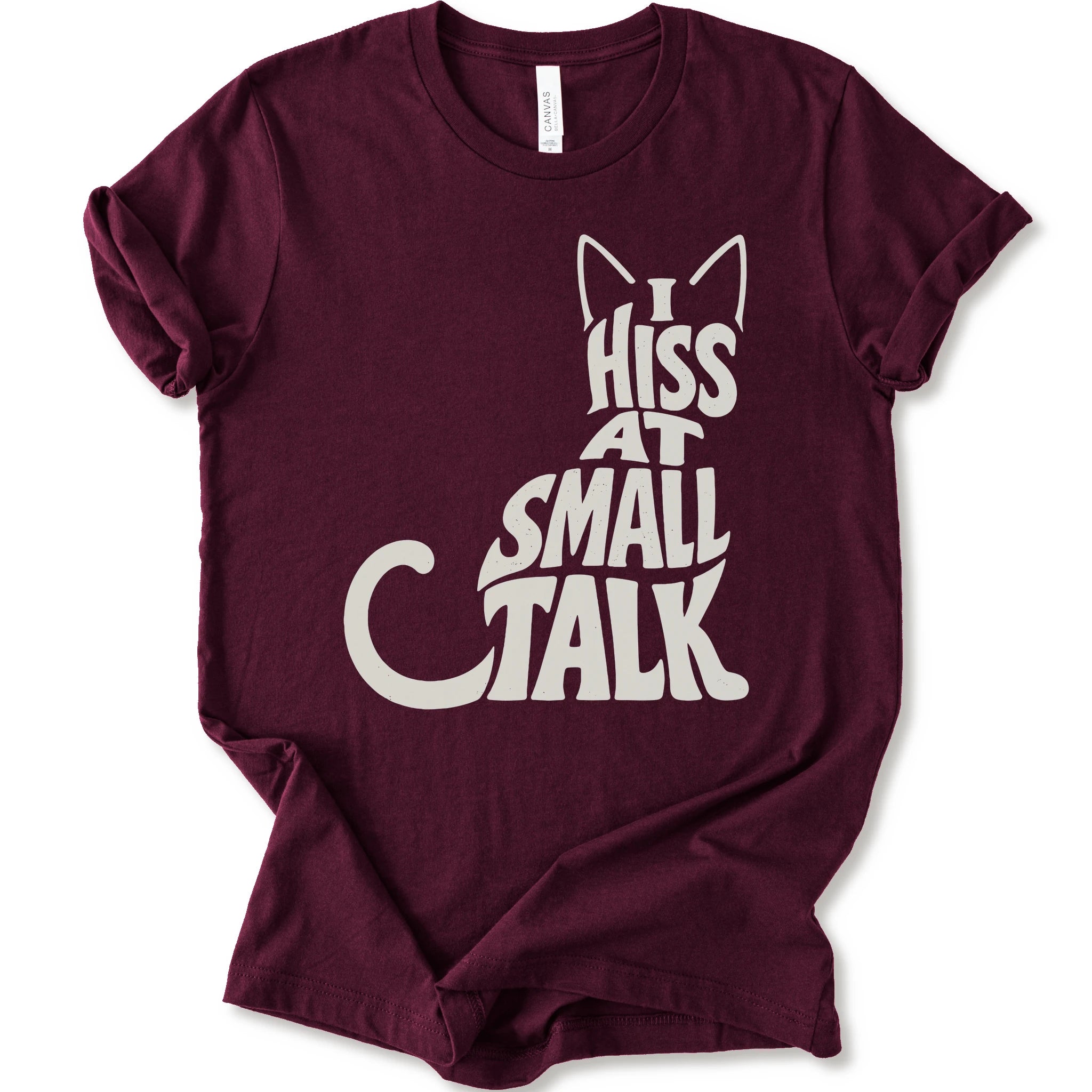 Maroon graphic t-shirt with off-white “I Hiss at Small Talk” typography with pointed cat ears and a large curved tail