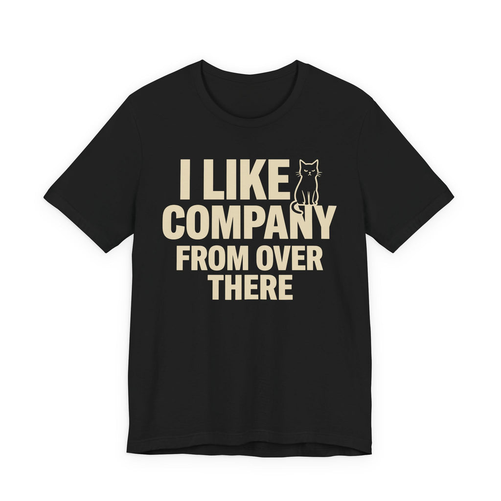 A black short-sleeve t-shirt with a beige graphic print that reads "I Like Company From Over There" with an unimpressed sitting cat