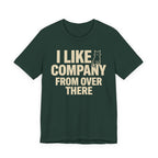 A forest short-sleeve t-shirt with a beige graphic print that reads "I Like Company From Over There" with an unimpressed sitting cat