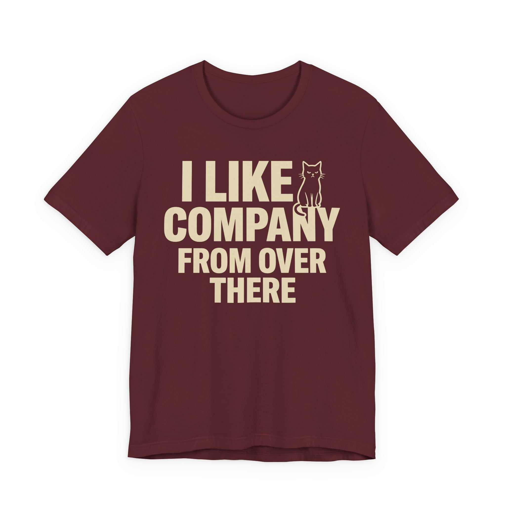 A maroon short-sleeve t-shirt with a beige graphic print that reads "I Like Company From Over There" with an unimpressed sitting cat