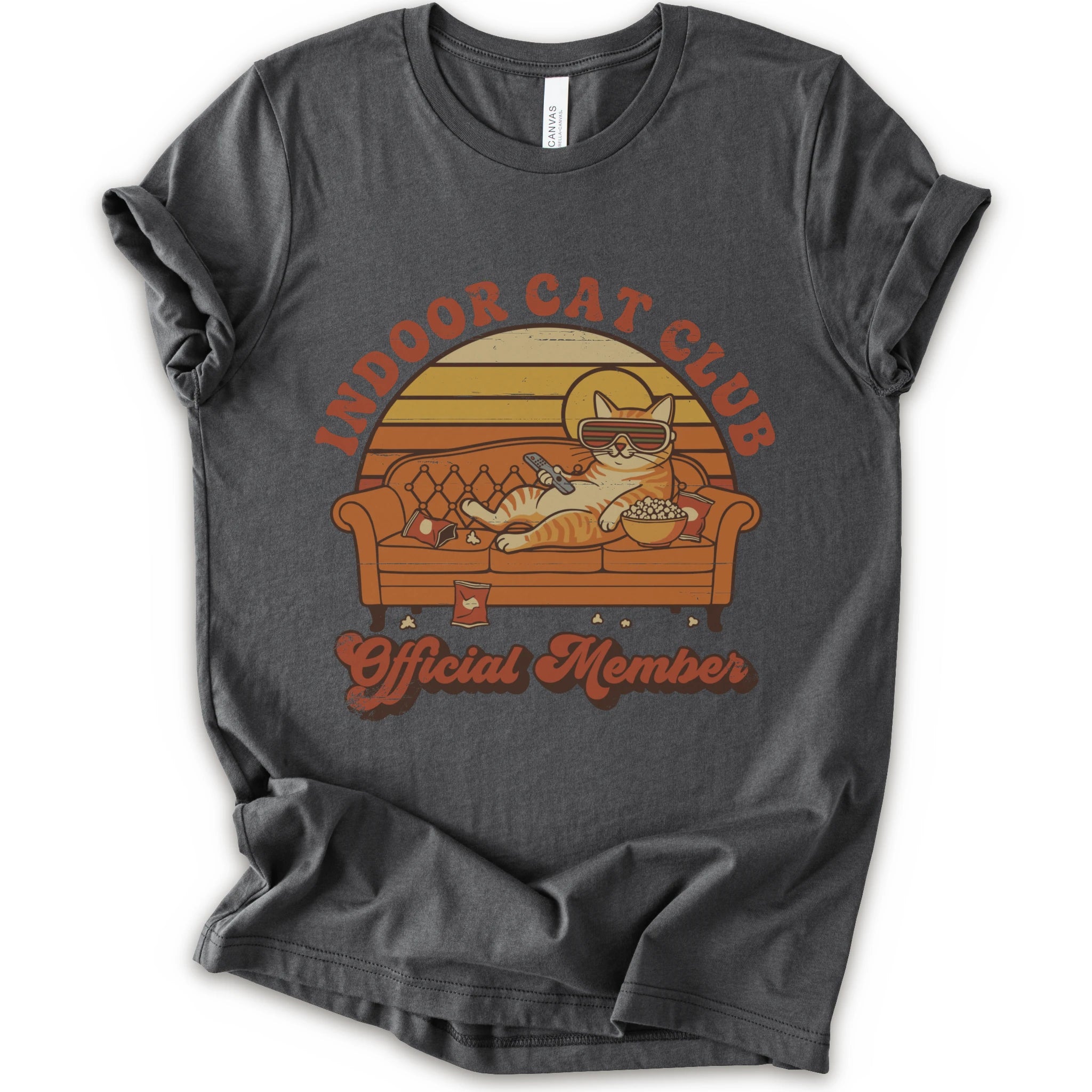 A asphalt short-sleeve crewneck t-shirt featuring a retro-style graphic of a cat lounging on a couch with the text 'INDOOR CAT CLUB' and 'Official Member' in orange-brown lettering.
