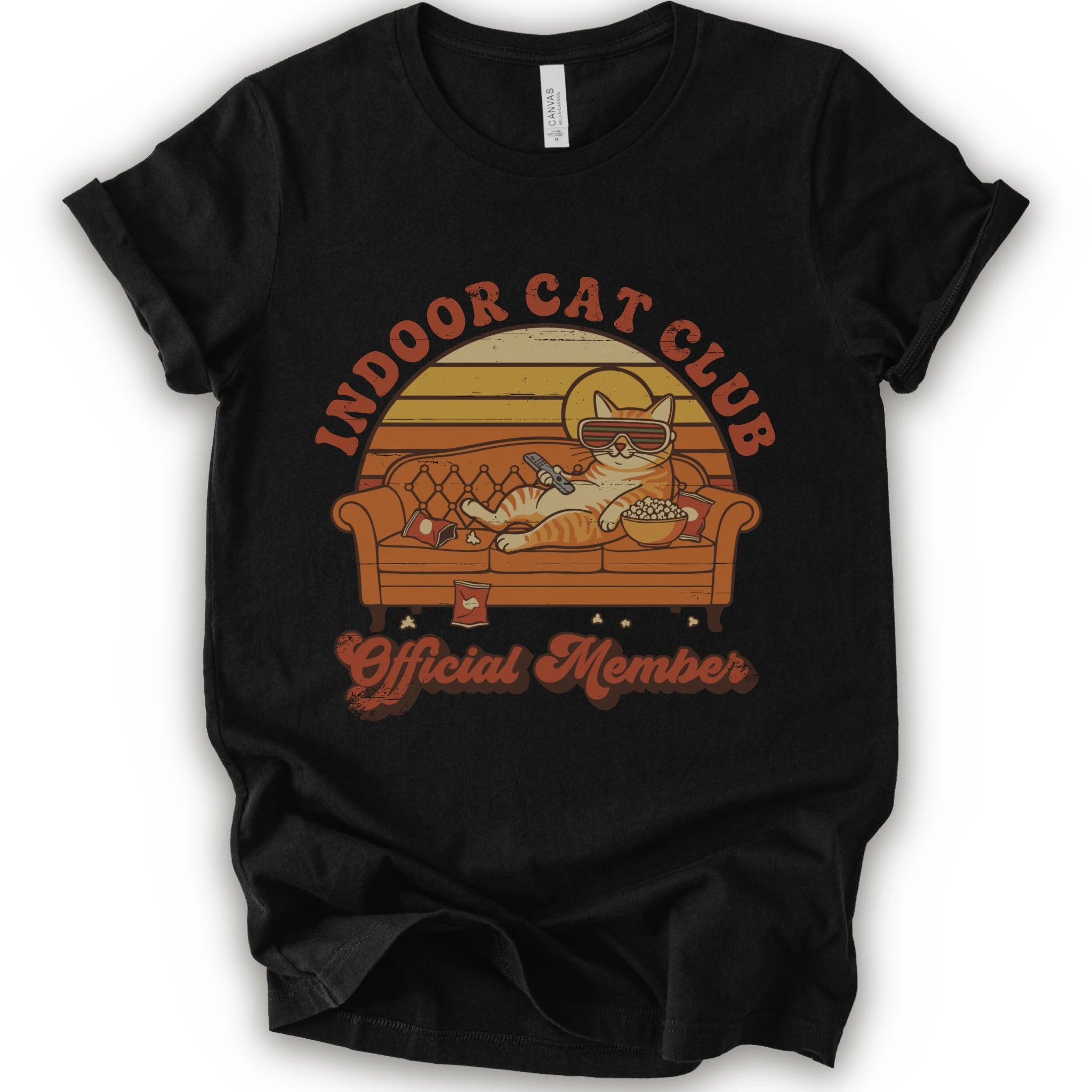 A black short-sleeve crewneck t-shirt featuring a retro-style graphic of a cat lounging on a couch with the text 'INDOOR CAT CLUB' and 'Official Member' in orange-brown lettering.